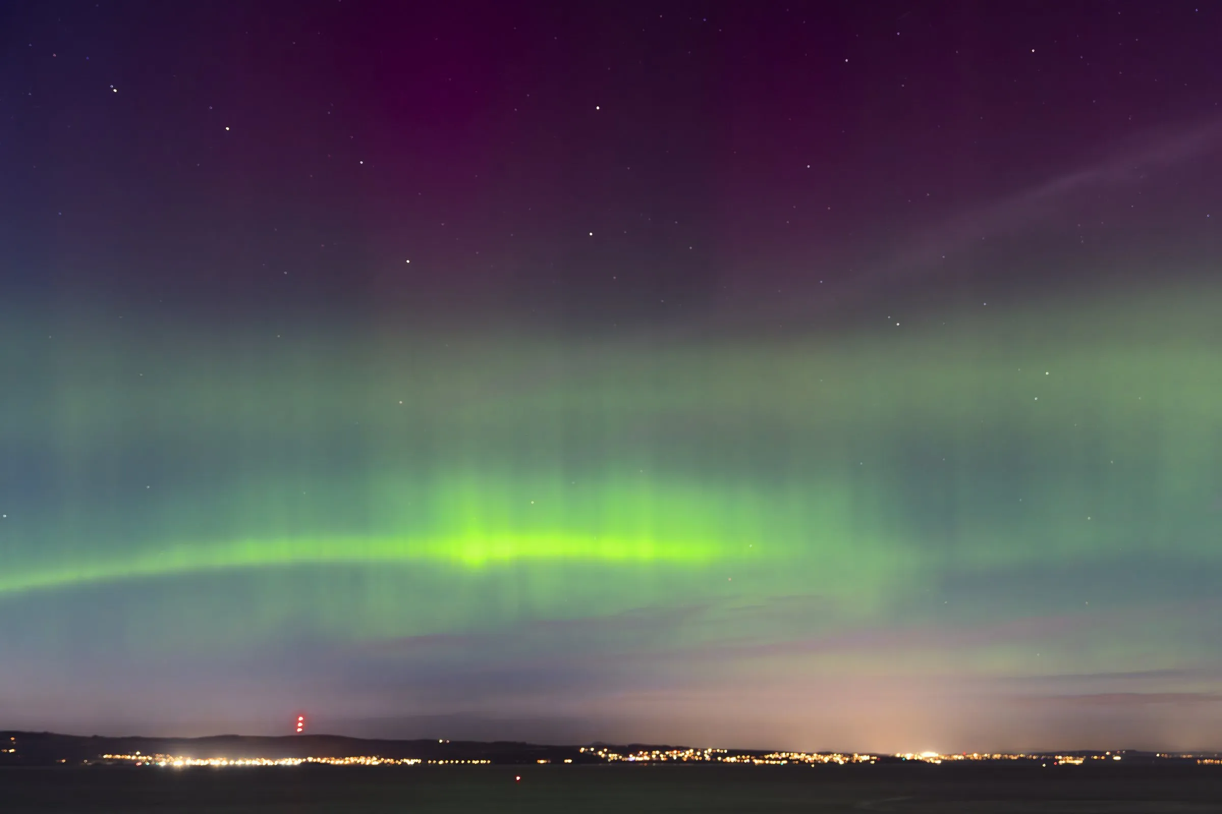A band of green aurora over the Firth of Forth and the lights along the far shore