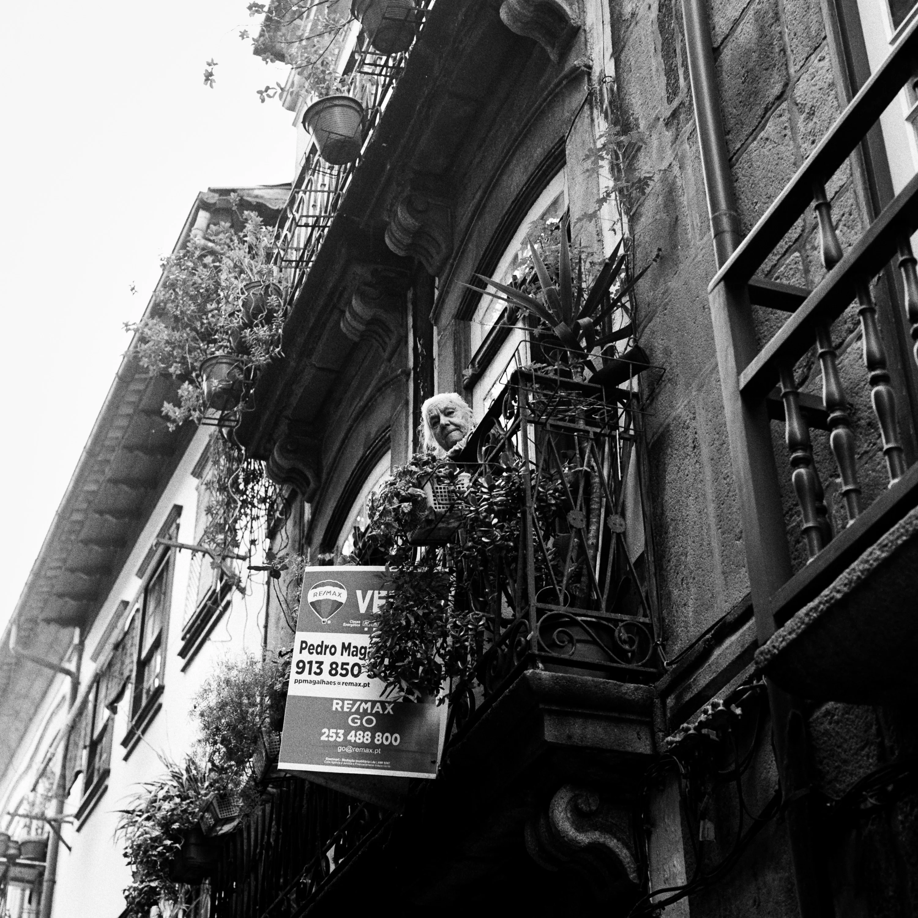 Black and white: old balconies and a sign on a narrow street