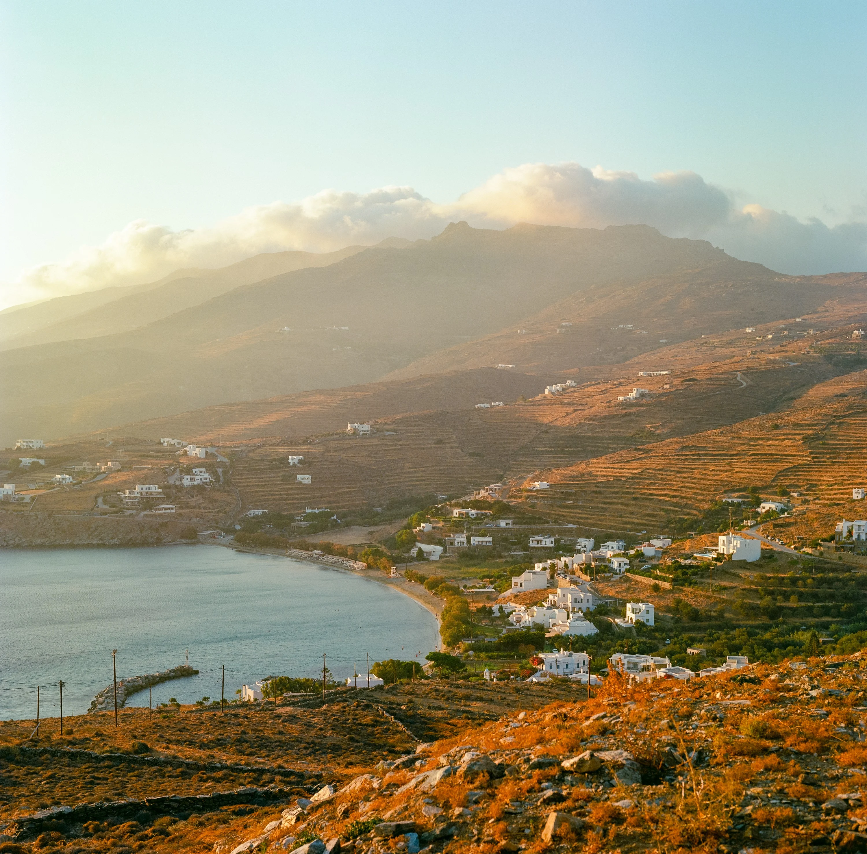 A bay and terraced hills in warm evening light, white villages along the shore