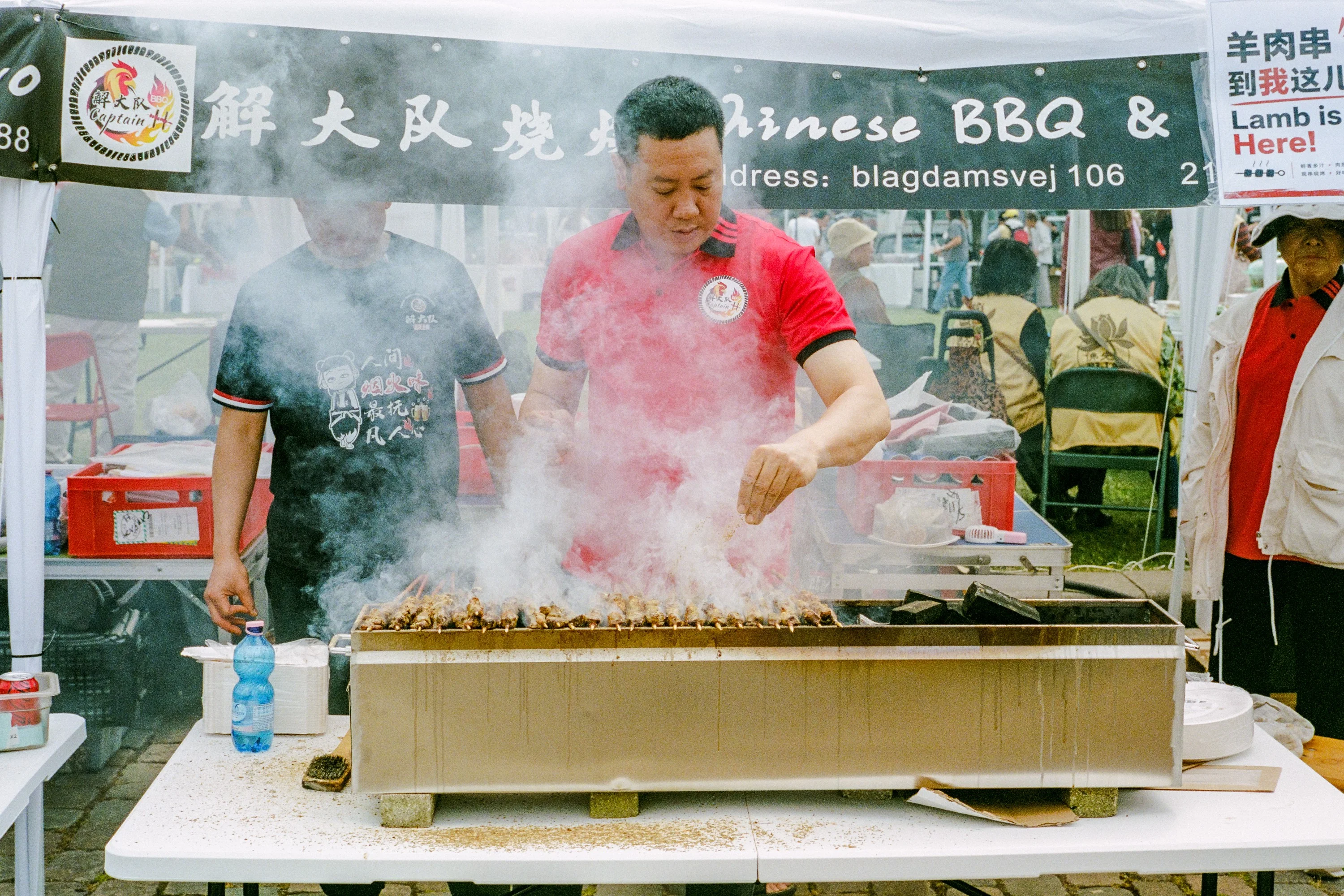 A cook working a smoking grill at a Chinese barbecue stall