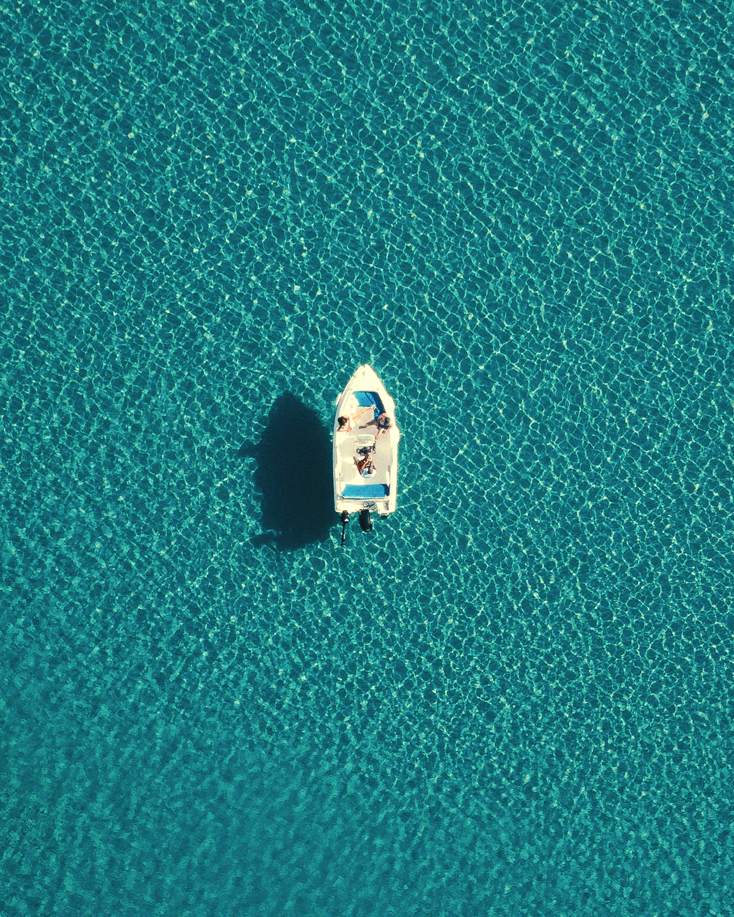 A small boat alone on turquoise water, seen from directly above