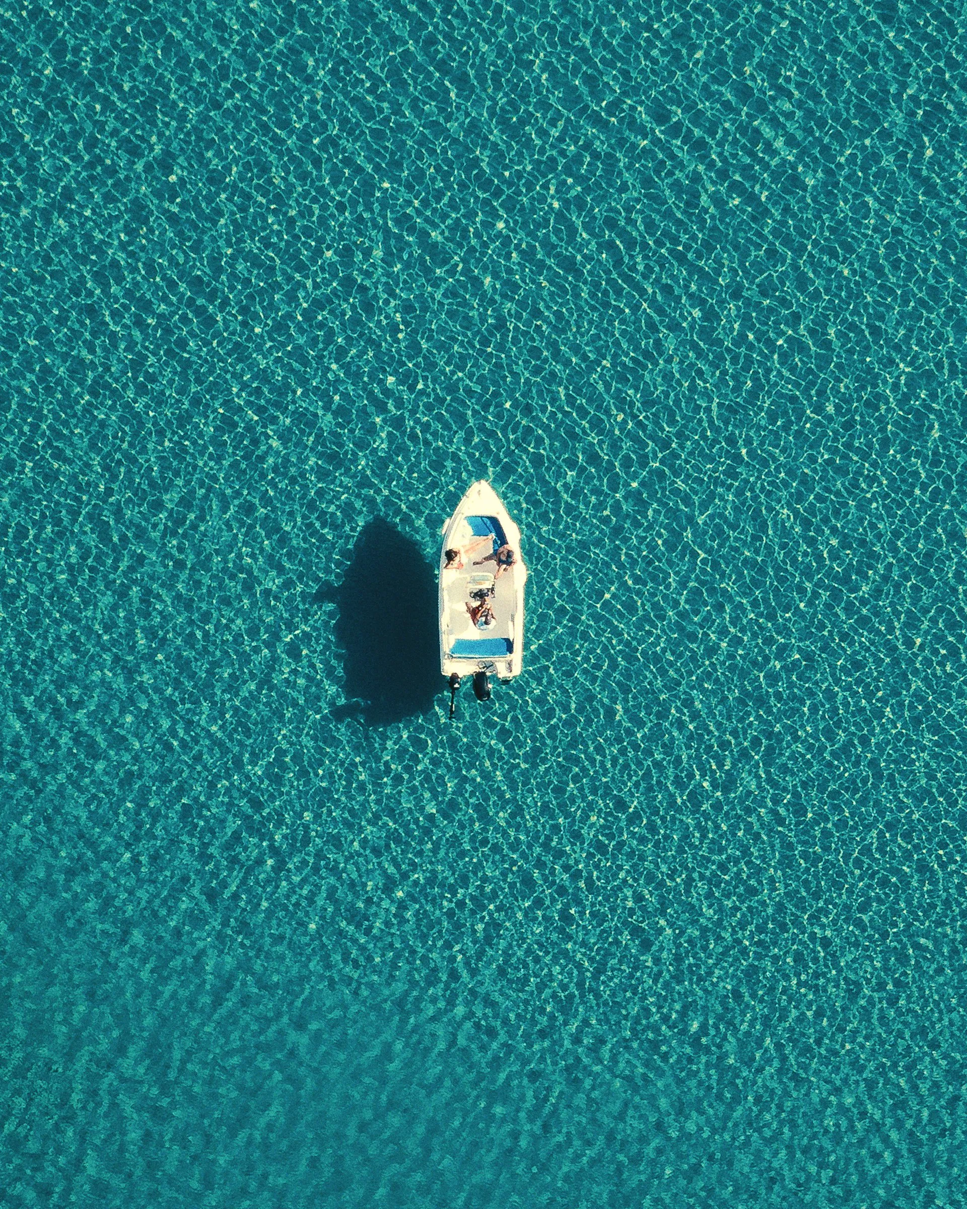 A small boat alone on turquoise water, seen from directly above