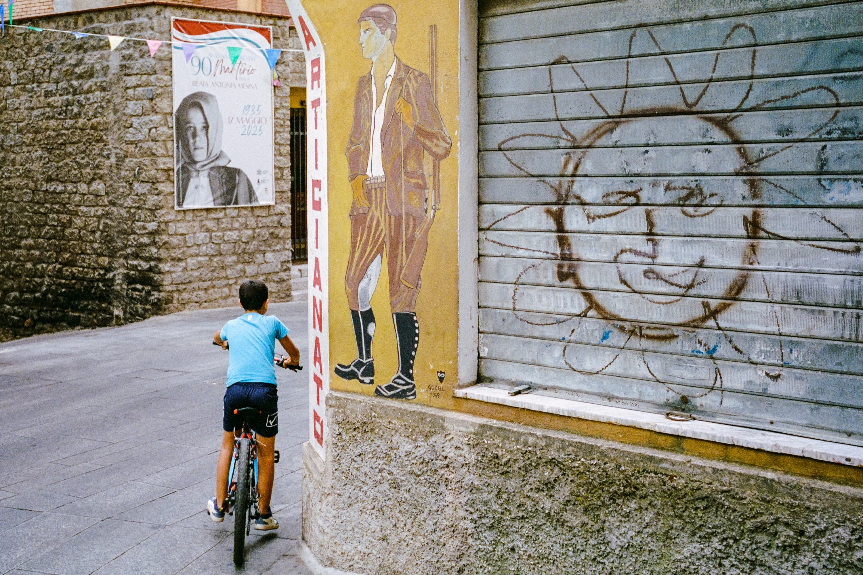 A boy on a bike riding past murals
