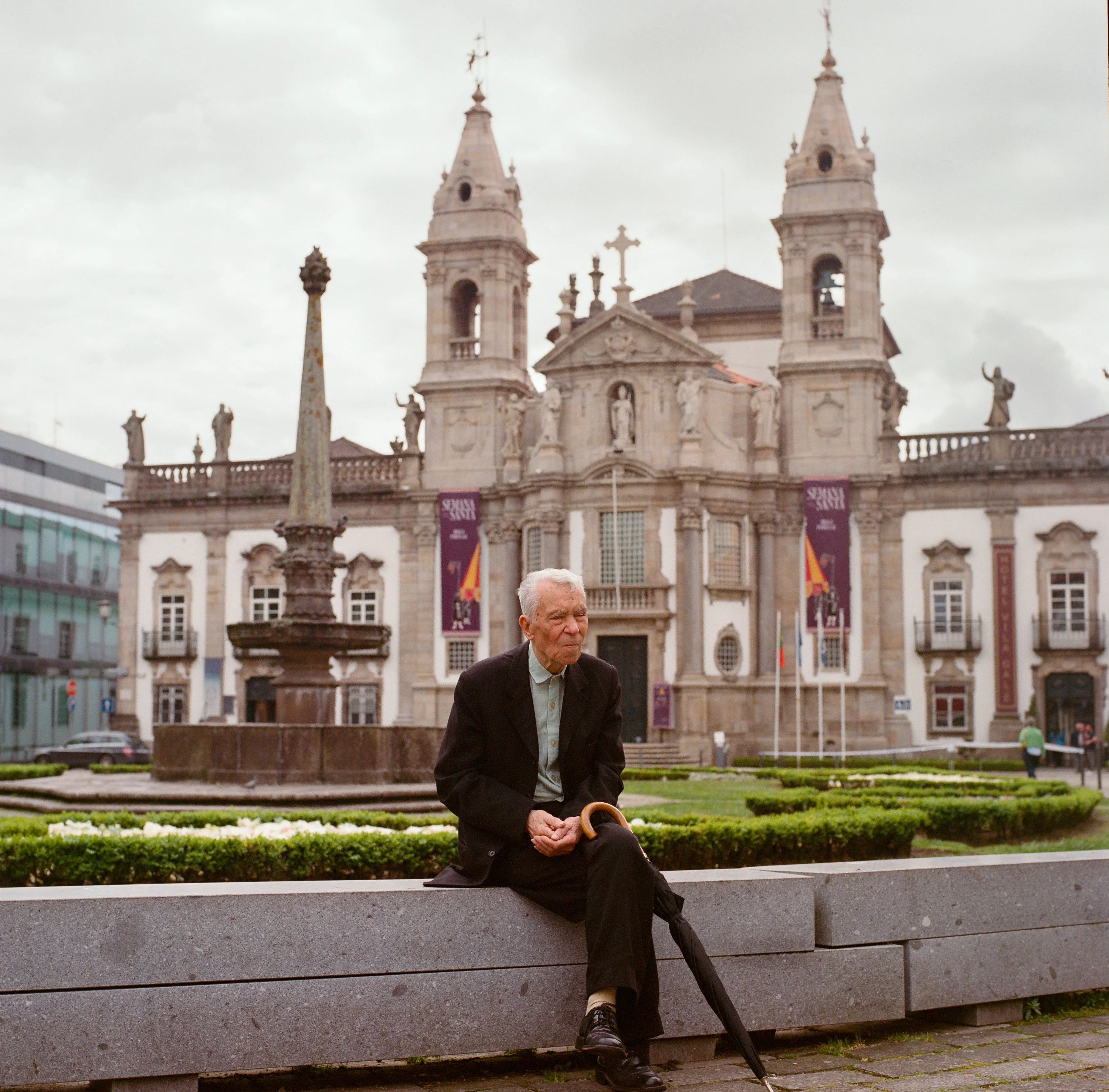 A man on a bench in front of a baroque church