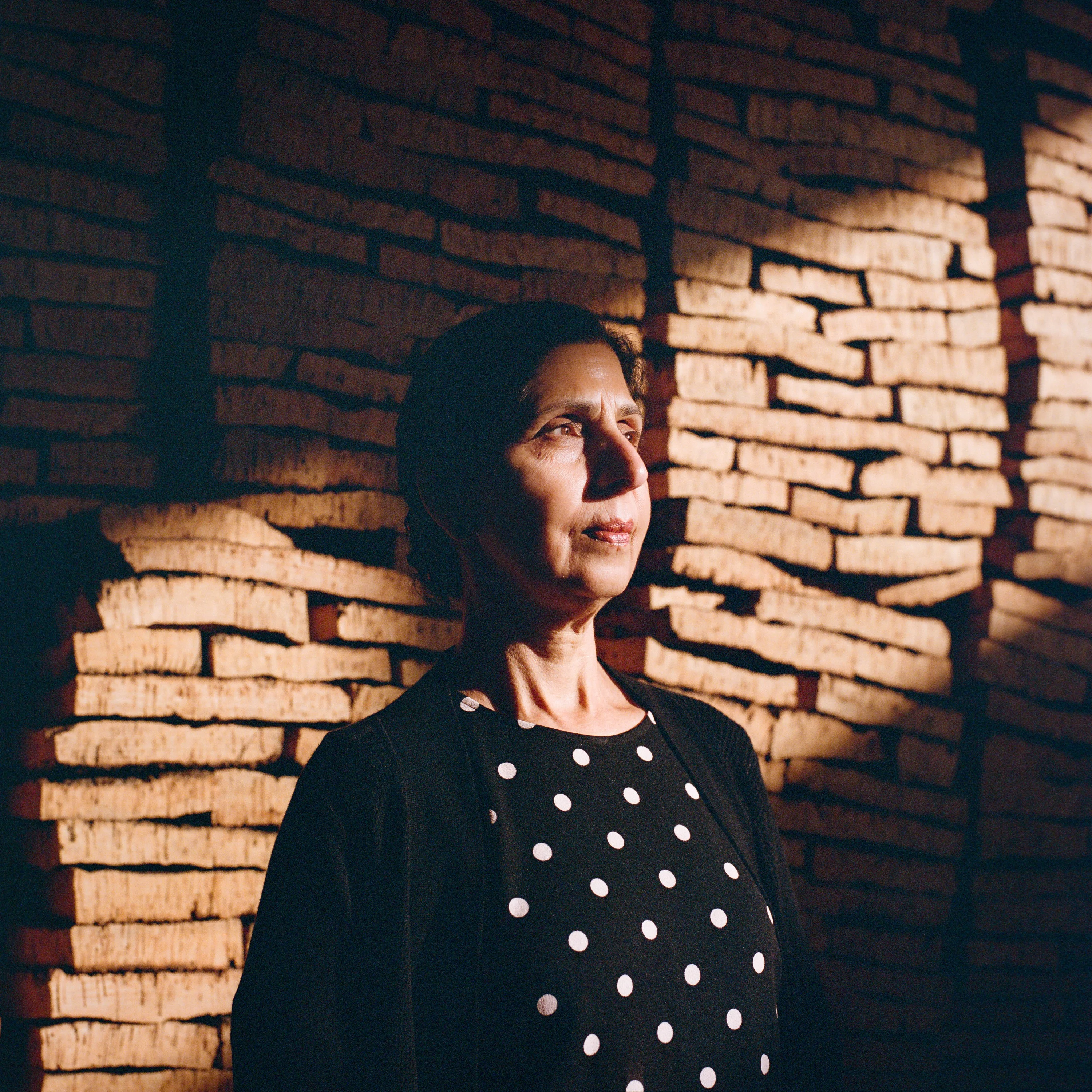A woman in polka dots against a sunlit brick wall
