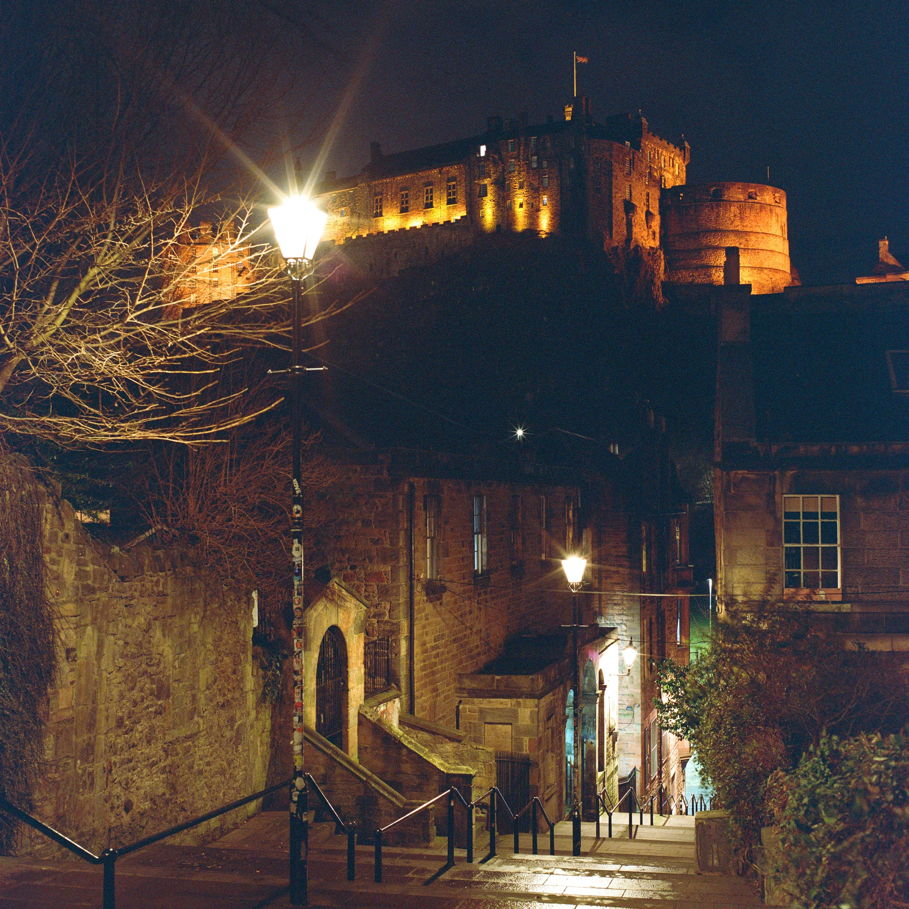 A narrow Old Town close at night with the castle lit above