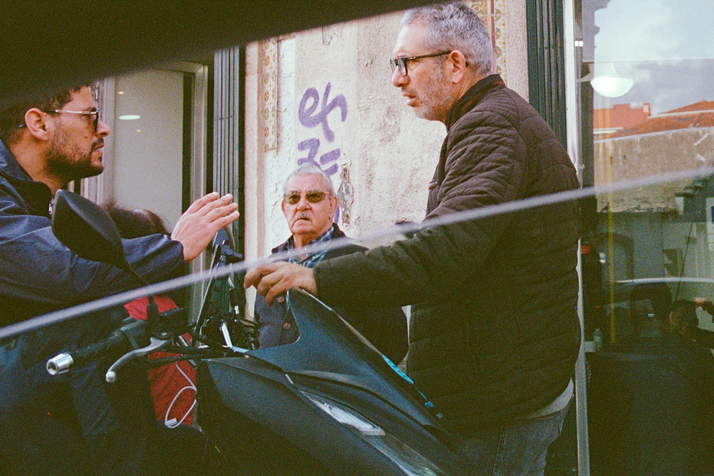 Two men talking by a motorbike
