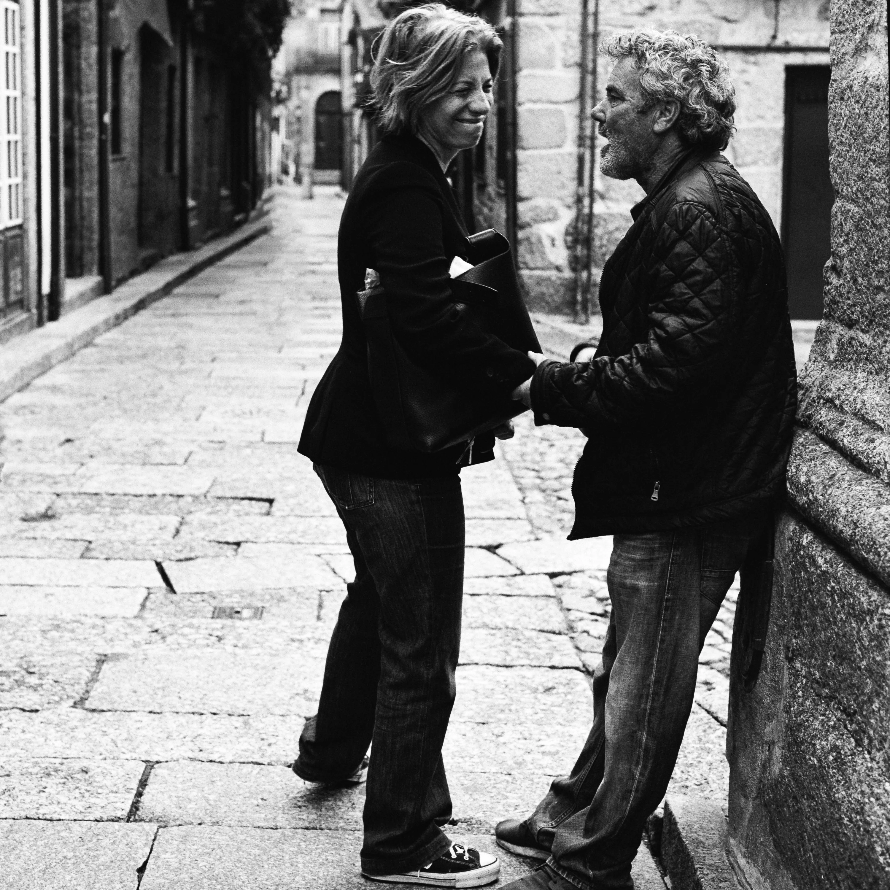 Black and white: a couple talking in a cobbled lane