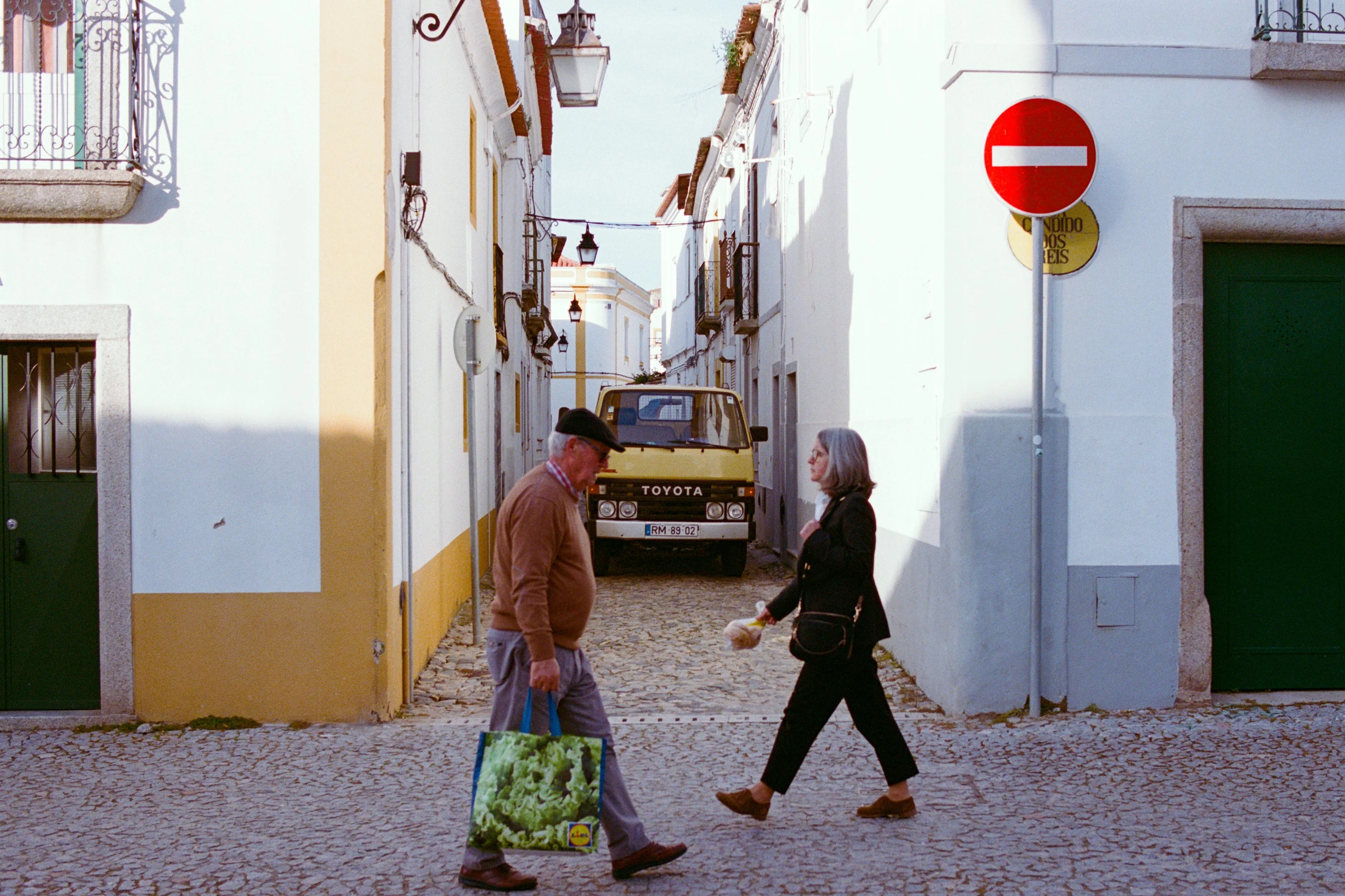 Two people passing on a white and yellow street
