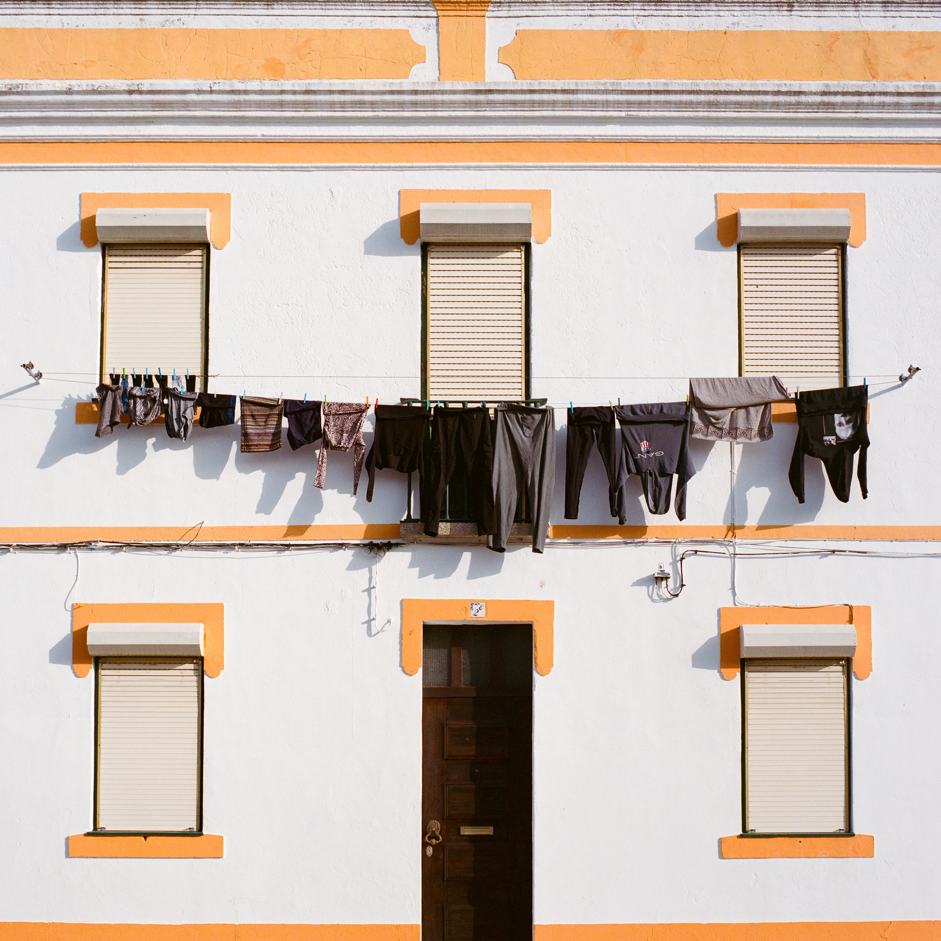 Laundry hung across the front of a white house with yellow window frames