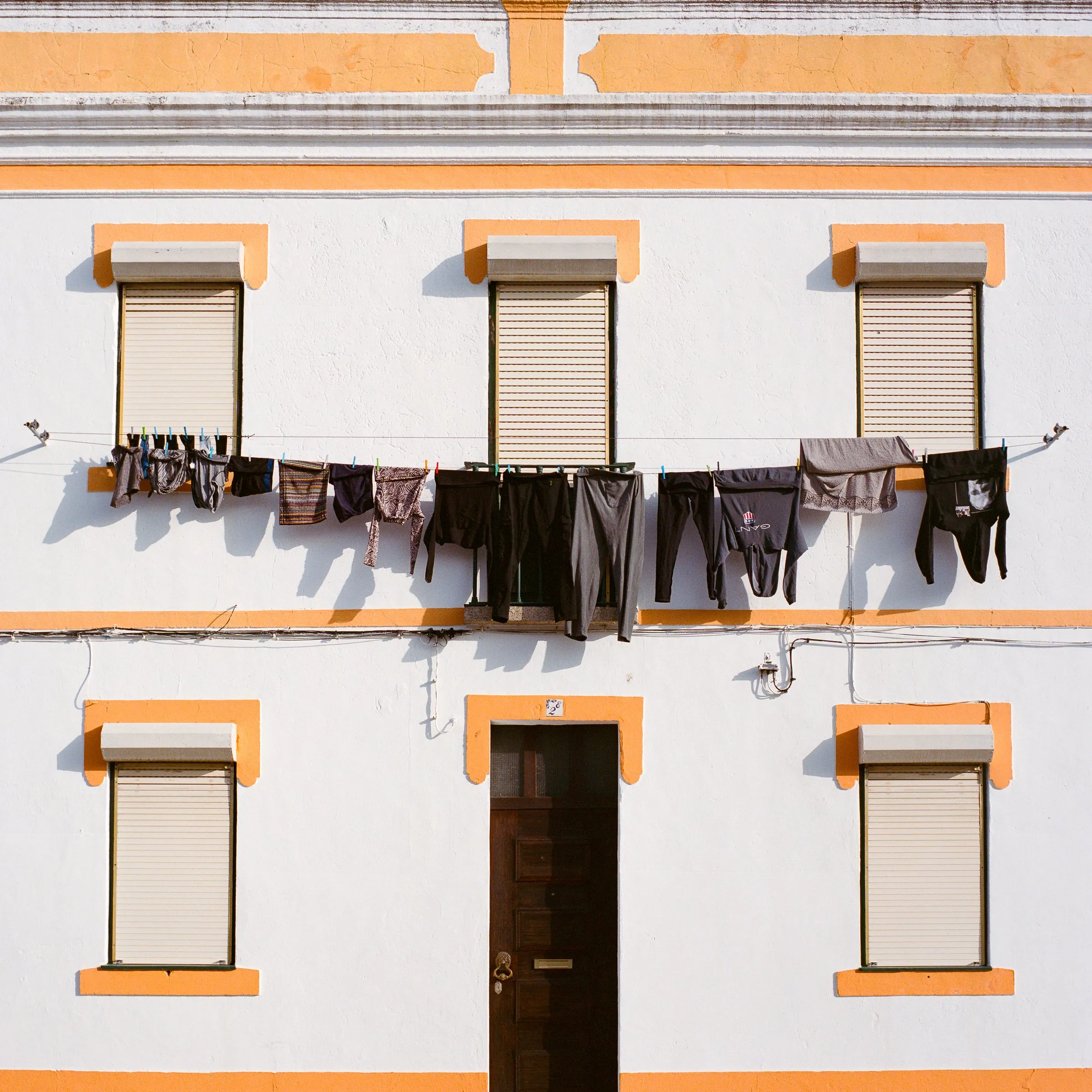 Laundry hung across the front of a white house with yellow window frames