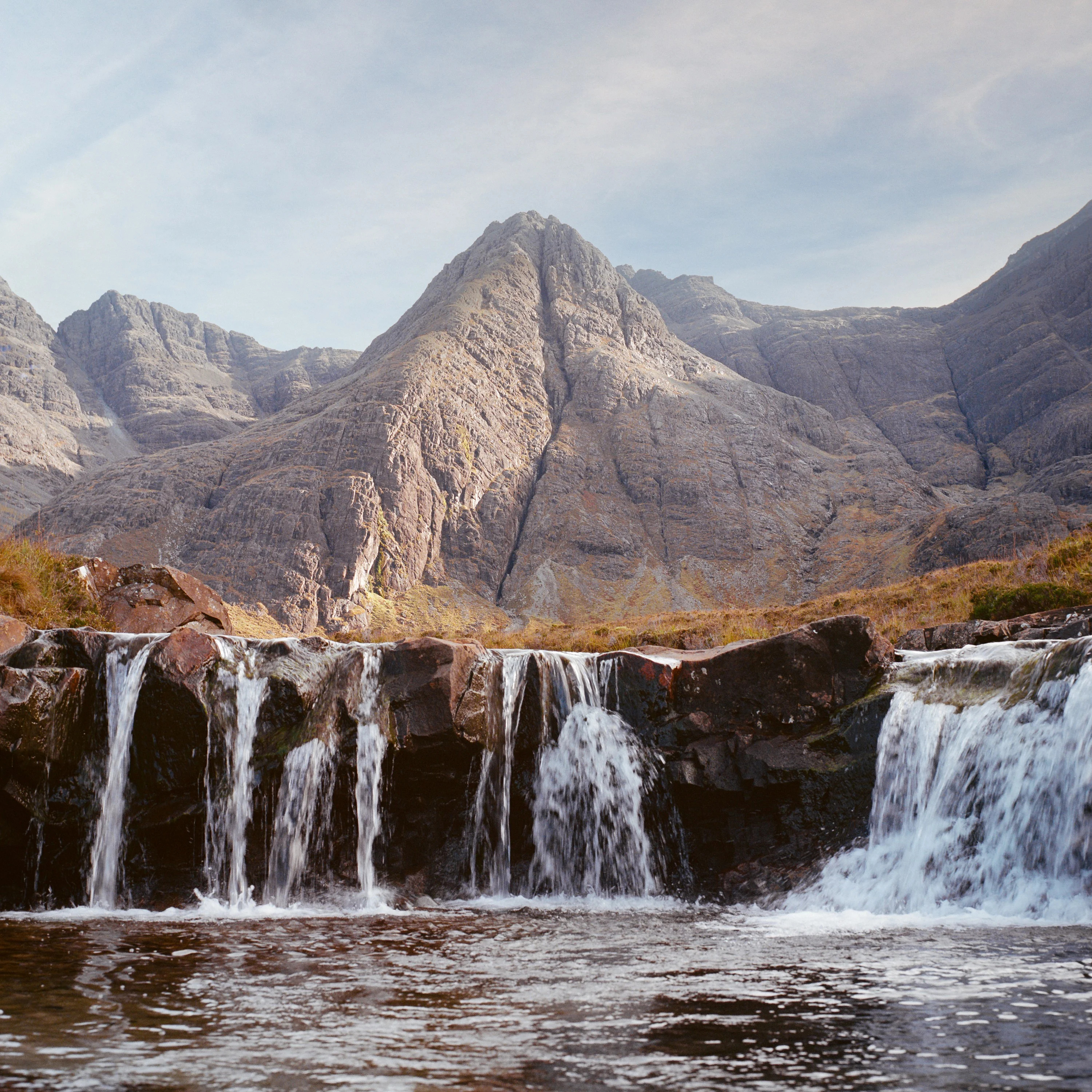 Waterfalls in front of the jagged Cuillin mountains