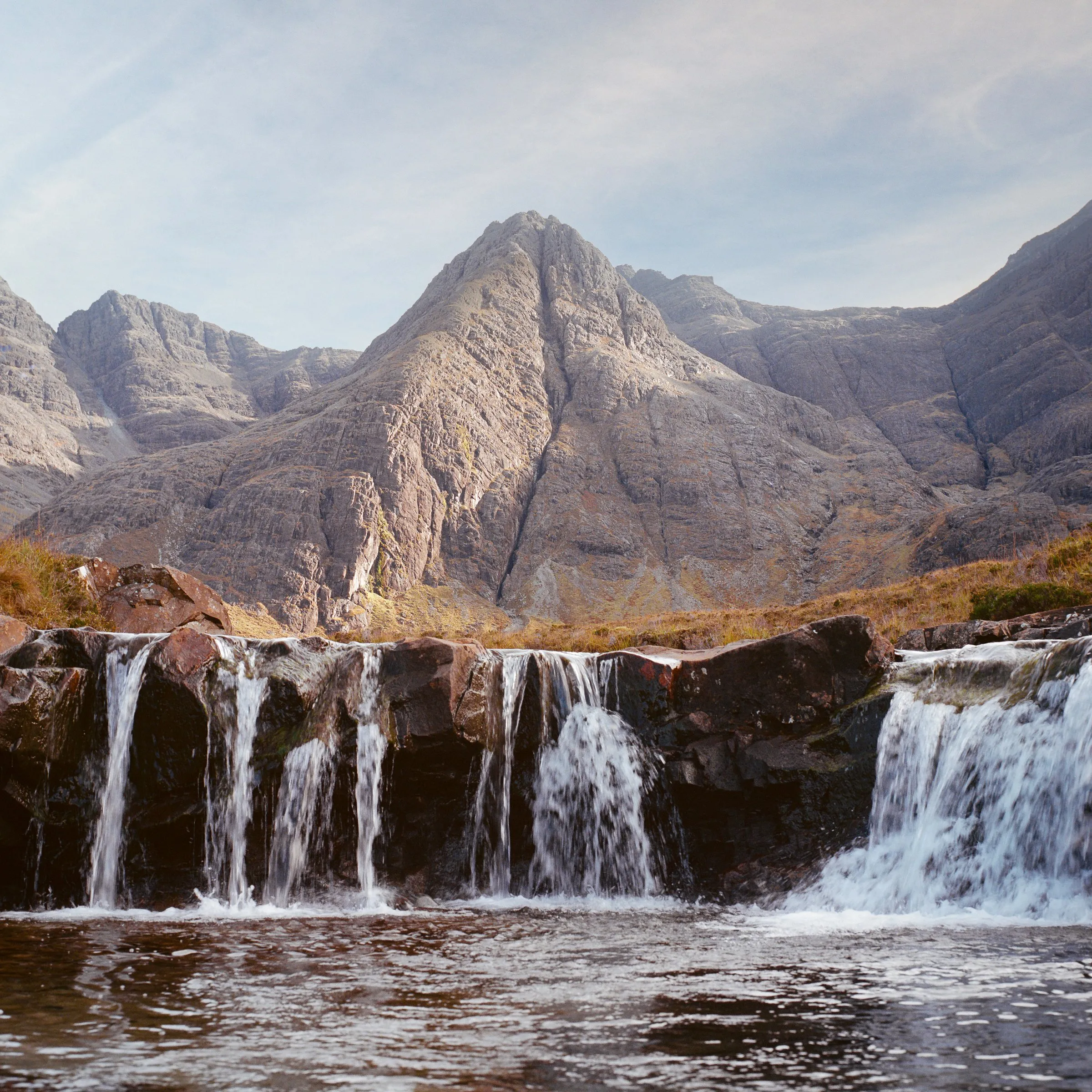 Waterfalls in front of the jagged Cuillin mountains
