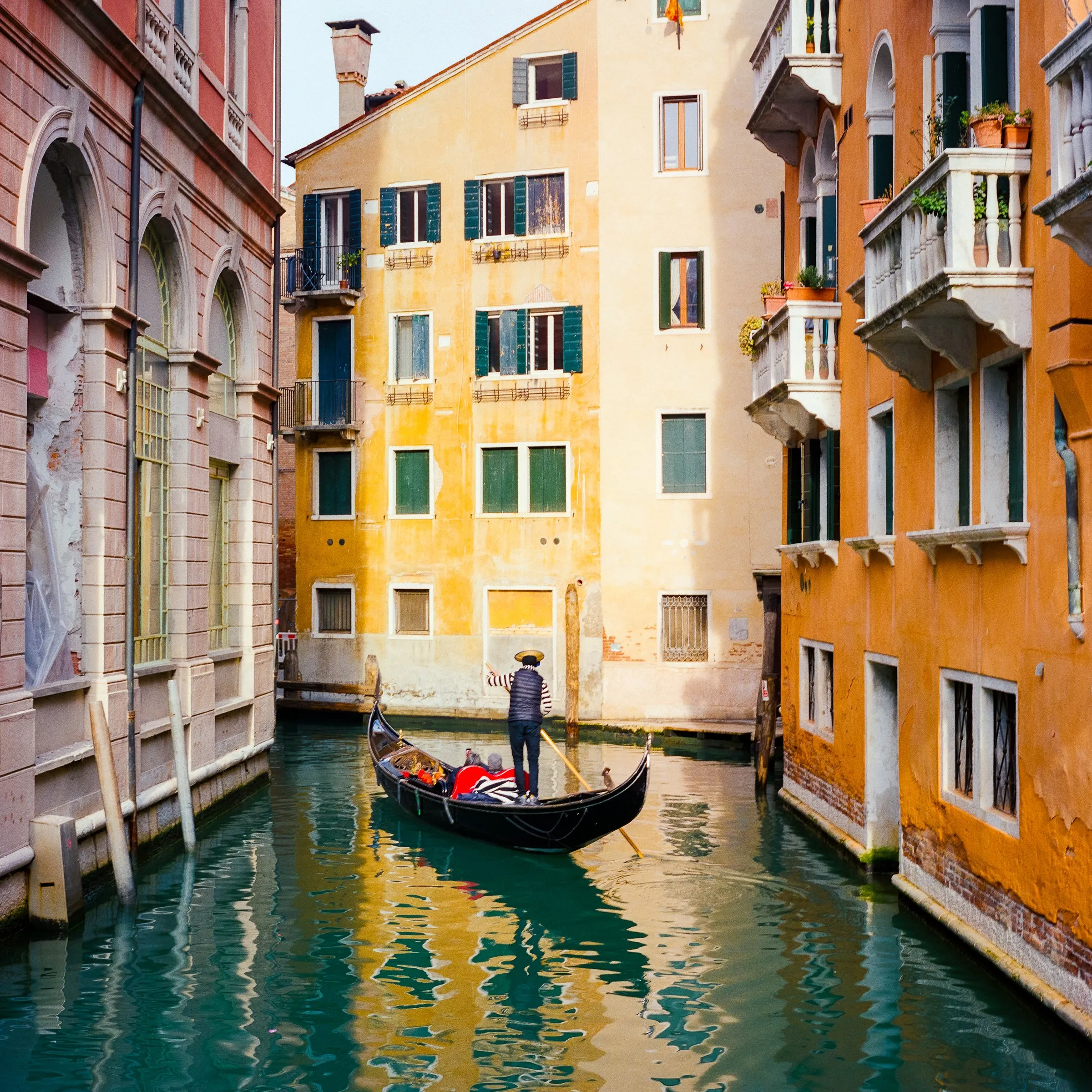 A gondola in a narrow canal between yellow walls