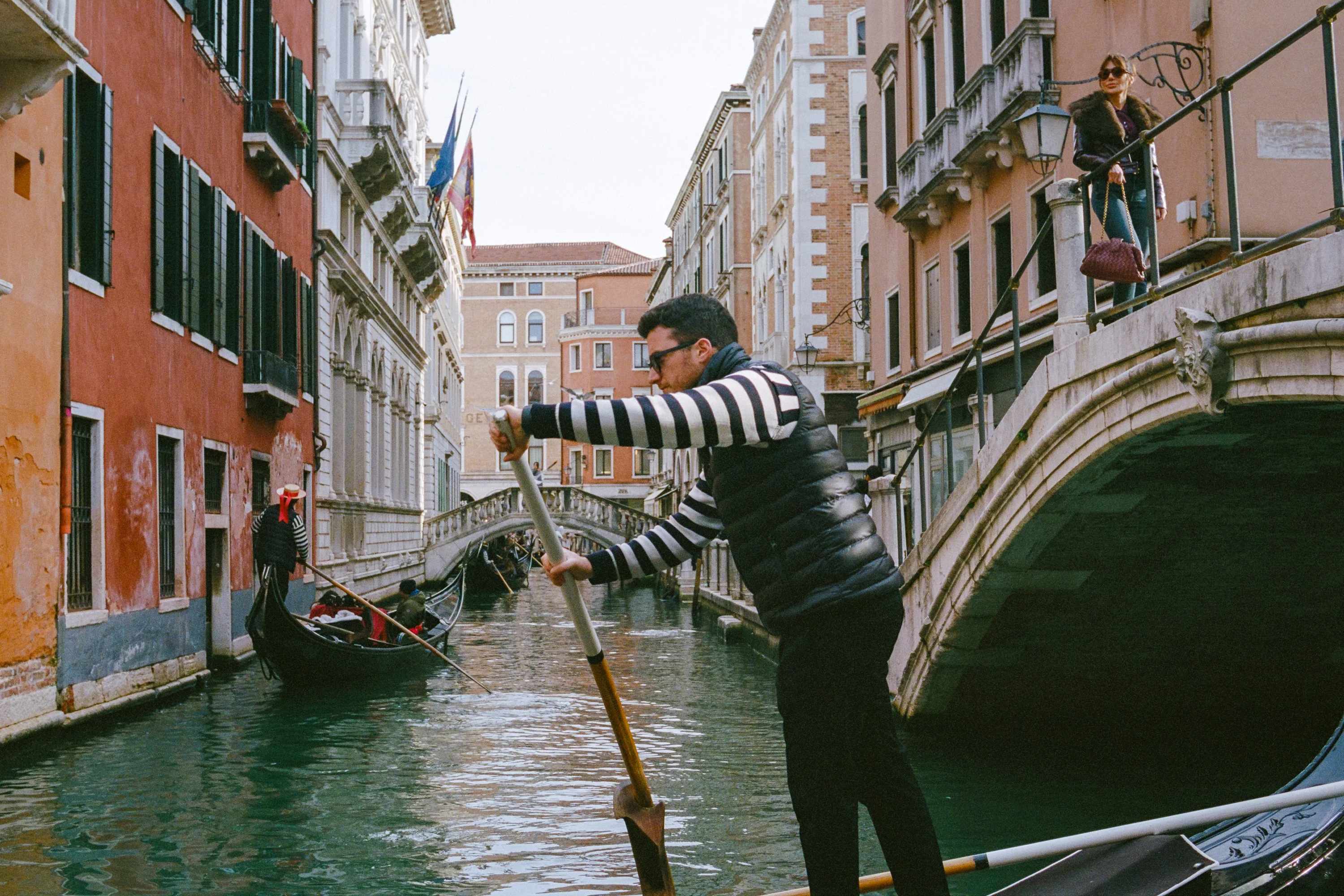 A gondolier rowing past a bridge