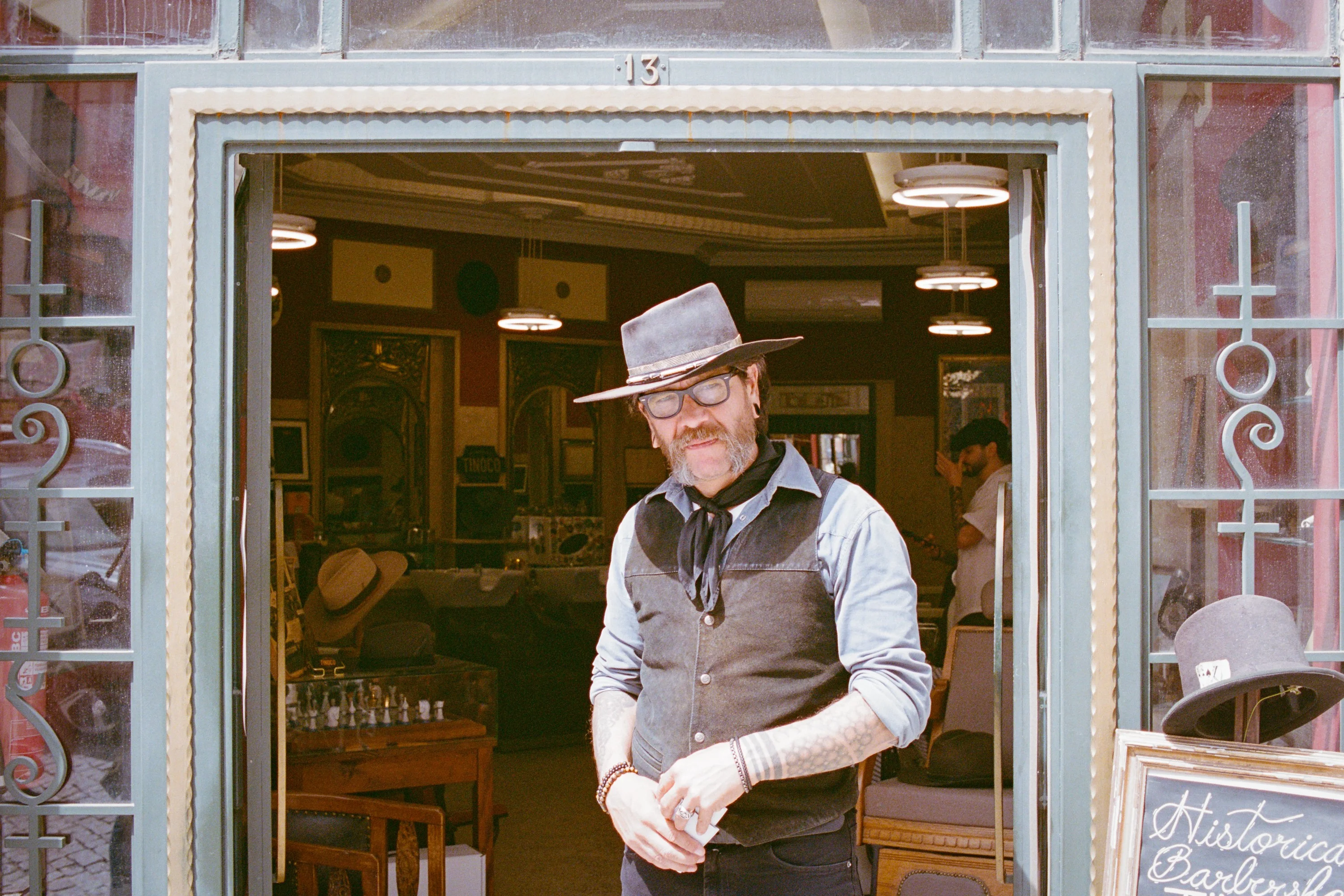 A man in a hat in the doorway of a hat shop