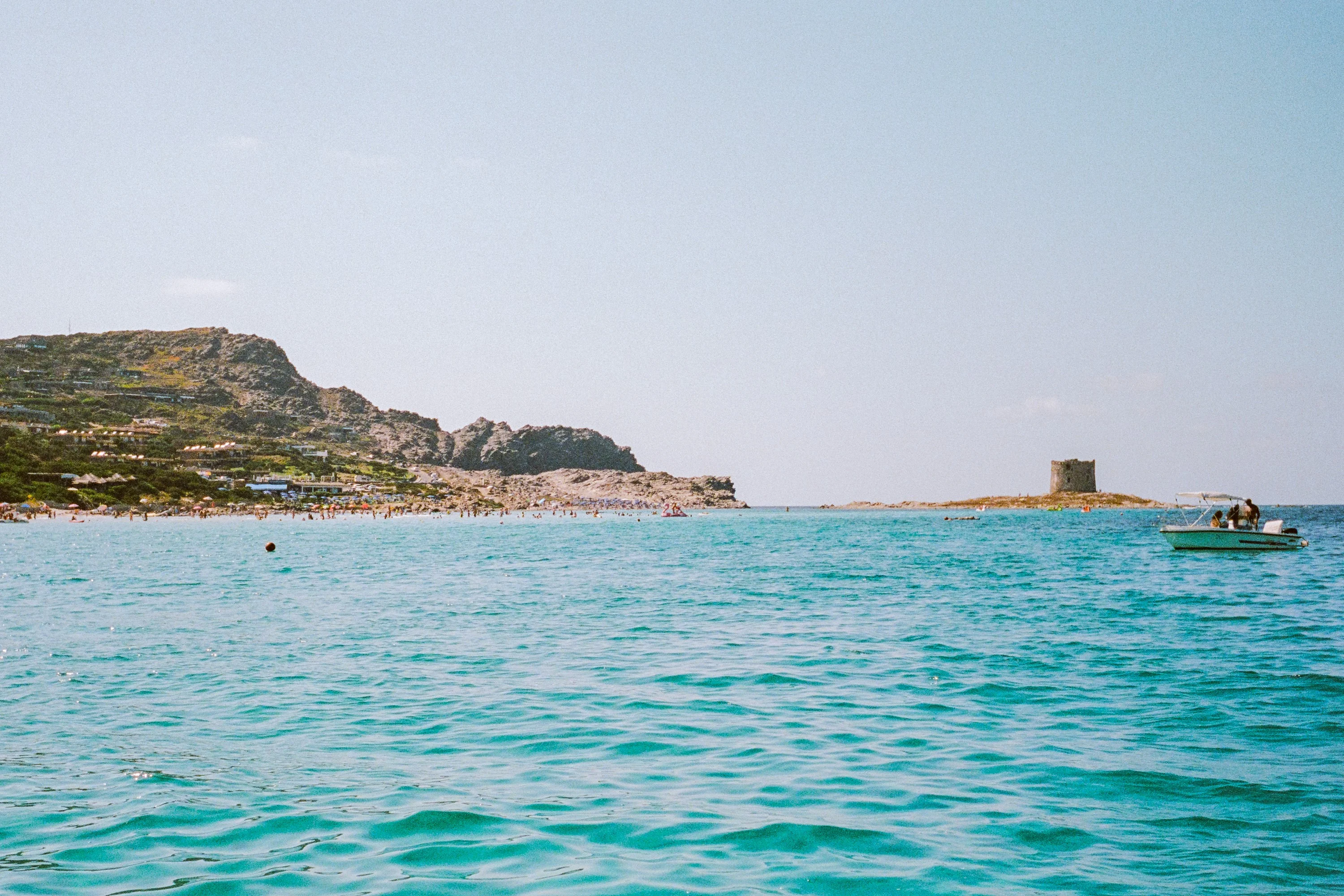Turquoise sea off La Pelosa, with a headland and an old watchtower on an islet