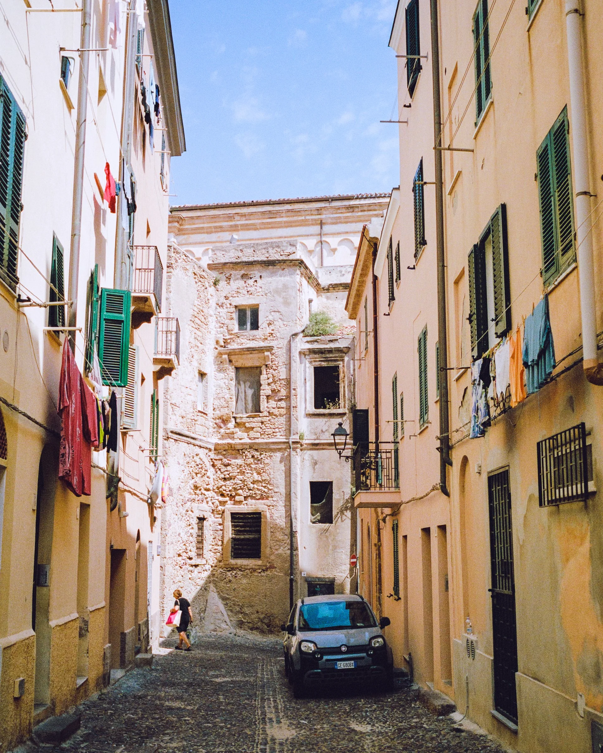 A narrow old-town lane with washing hung between tall faded houses
