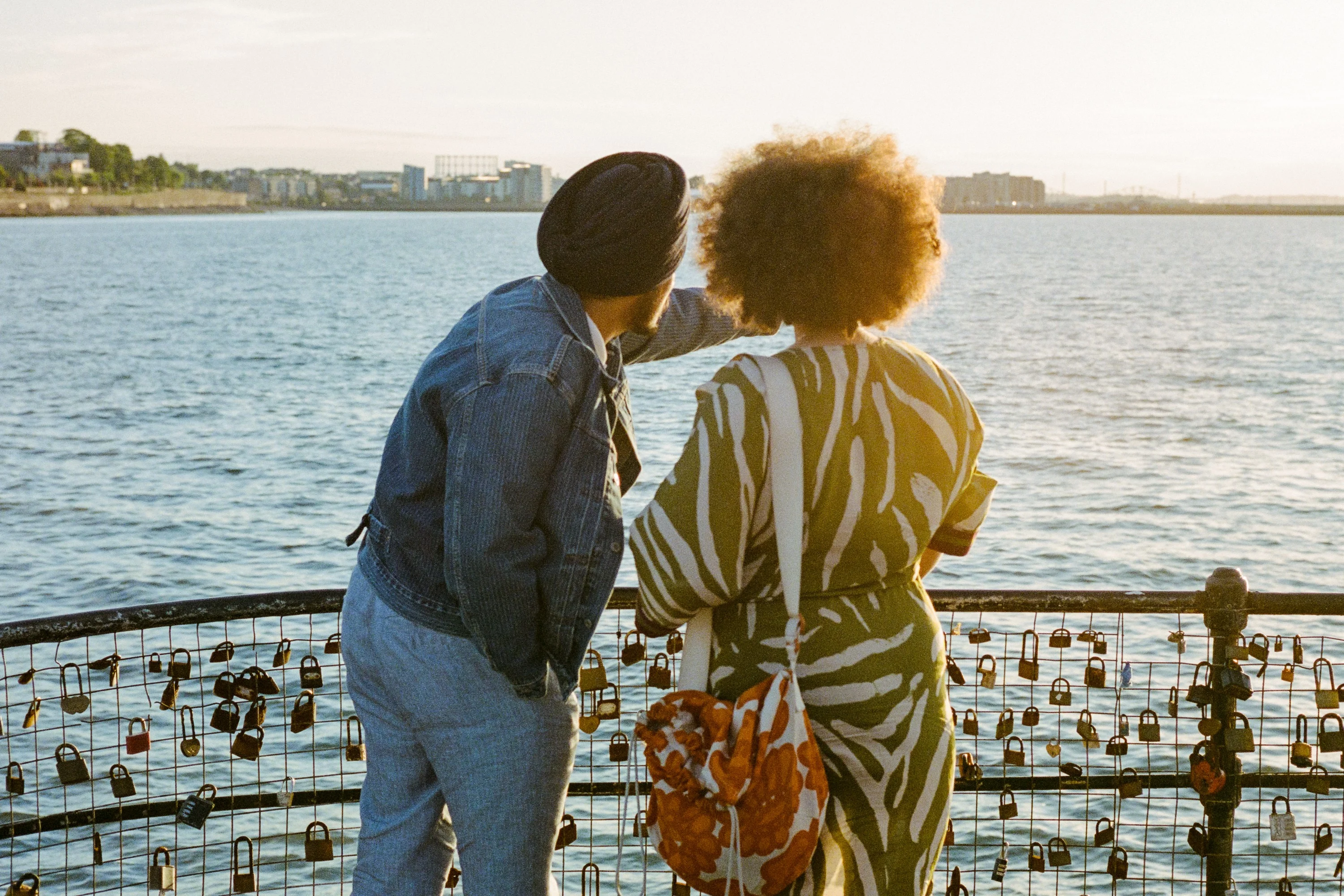 A couple kissing by railings covered in love locks
