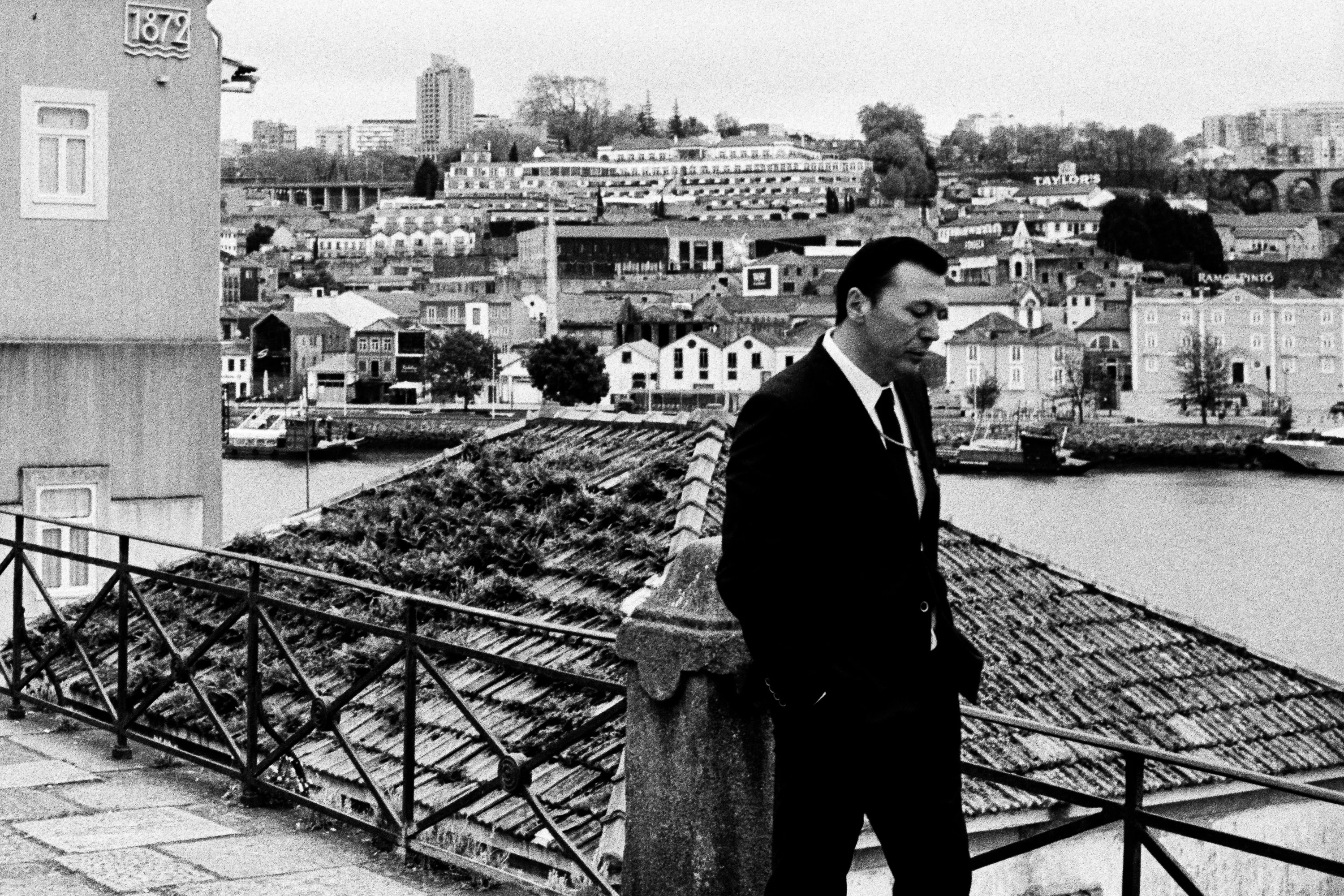 Black and white: a man in a suit on a terrace above the river