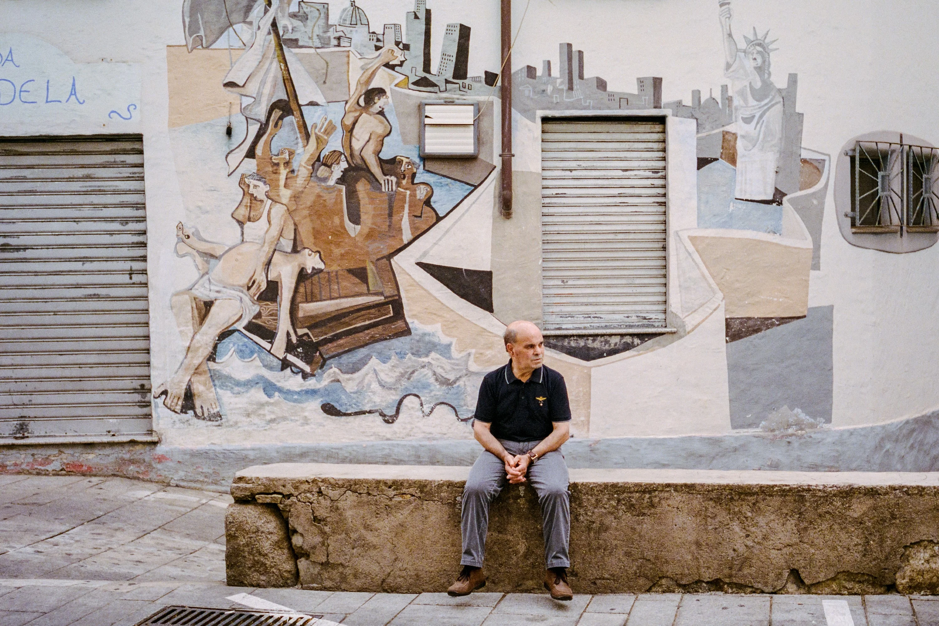 A man sitting under a mural