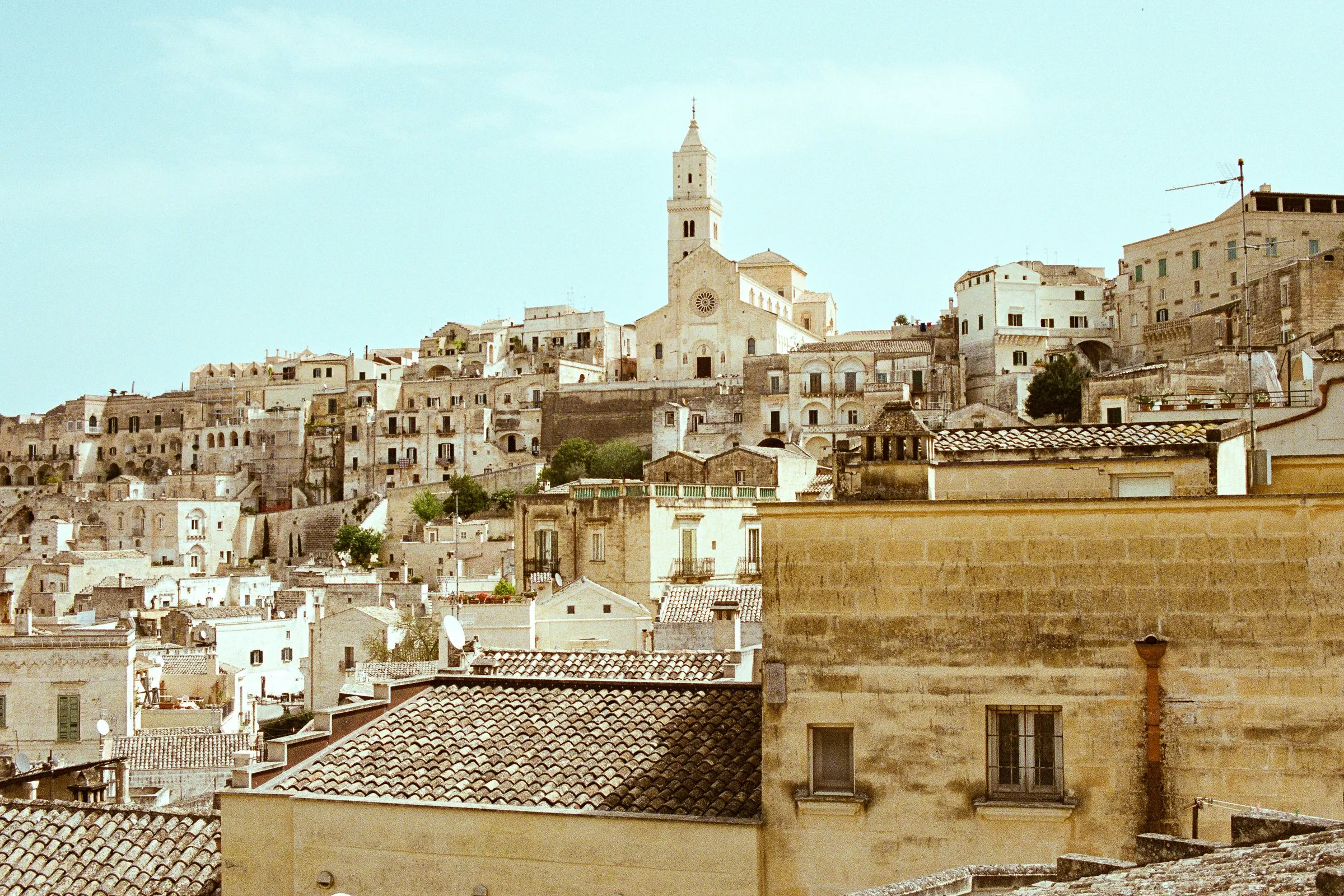 Matera's pale stone houses climbing to the cathedral bell tower in afternoon light