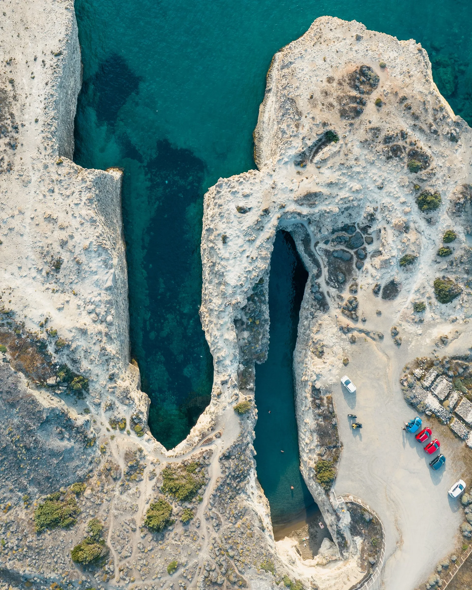 Aerial view of white volcanic rock and a deep green inlet