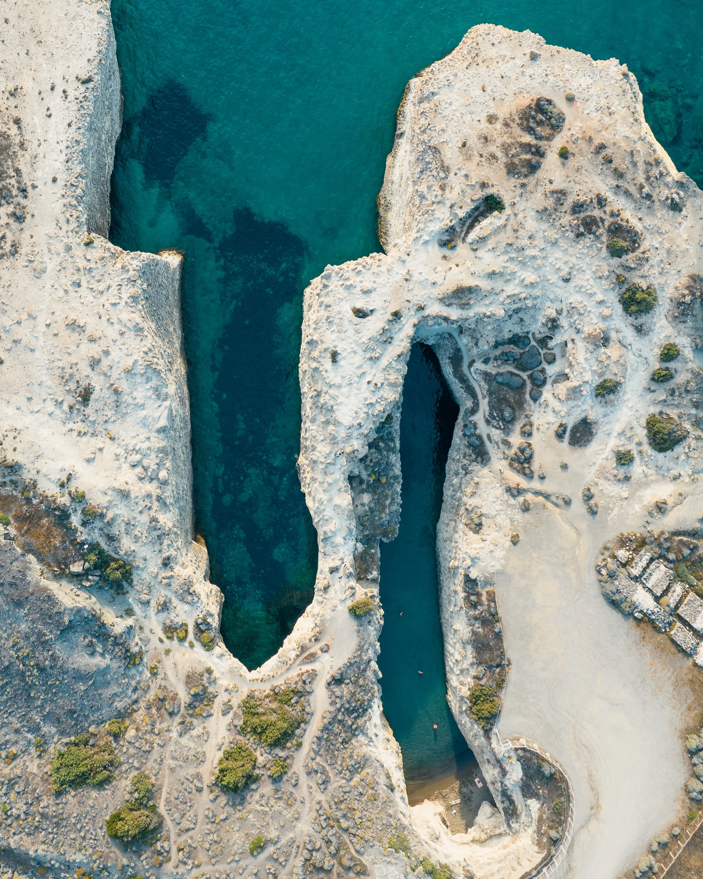 Aerial view of white volcanic rock and a deep green inlet