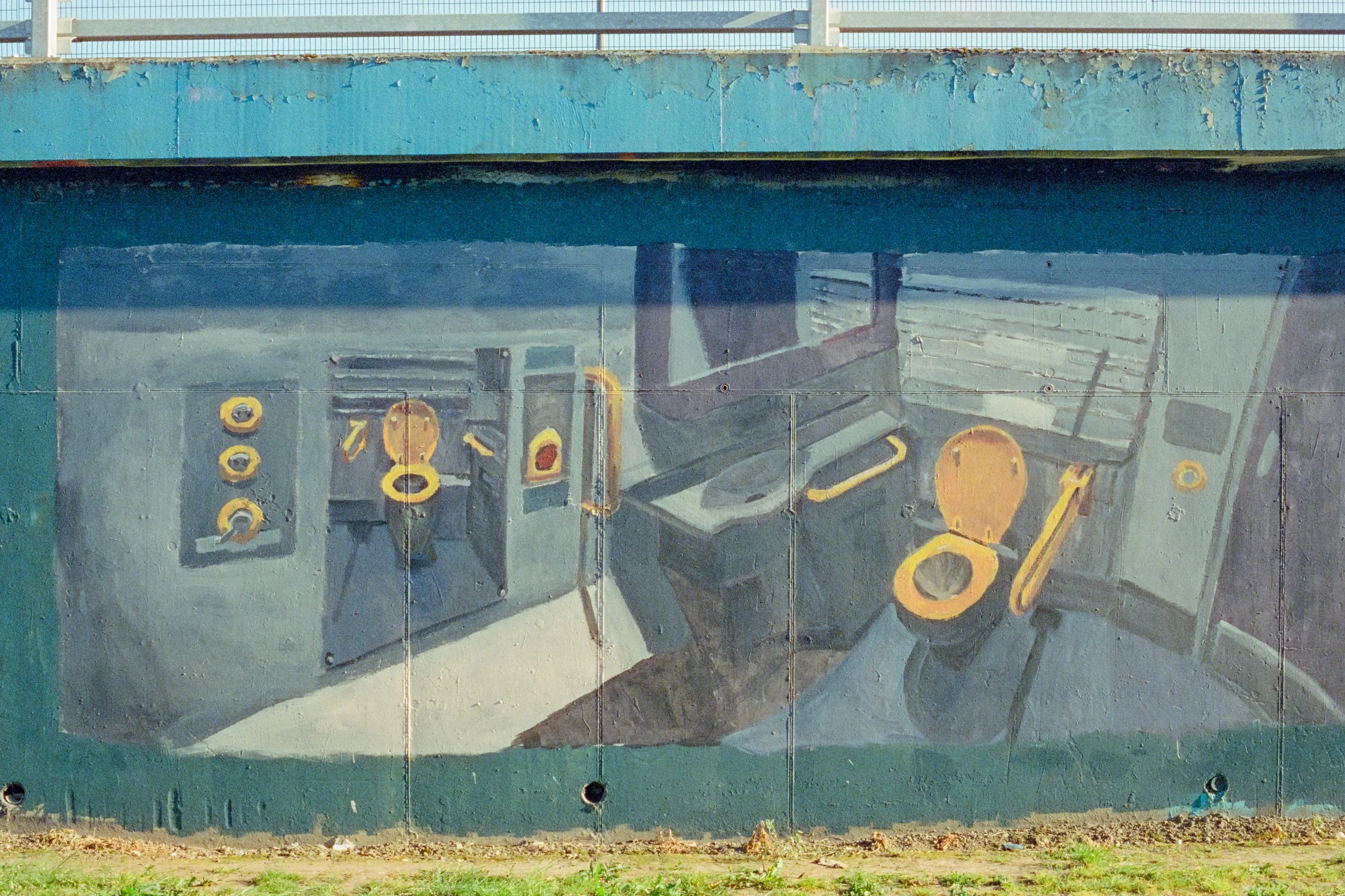 A painted mural of a bathroom on a boarded wall