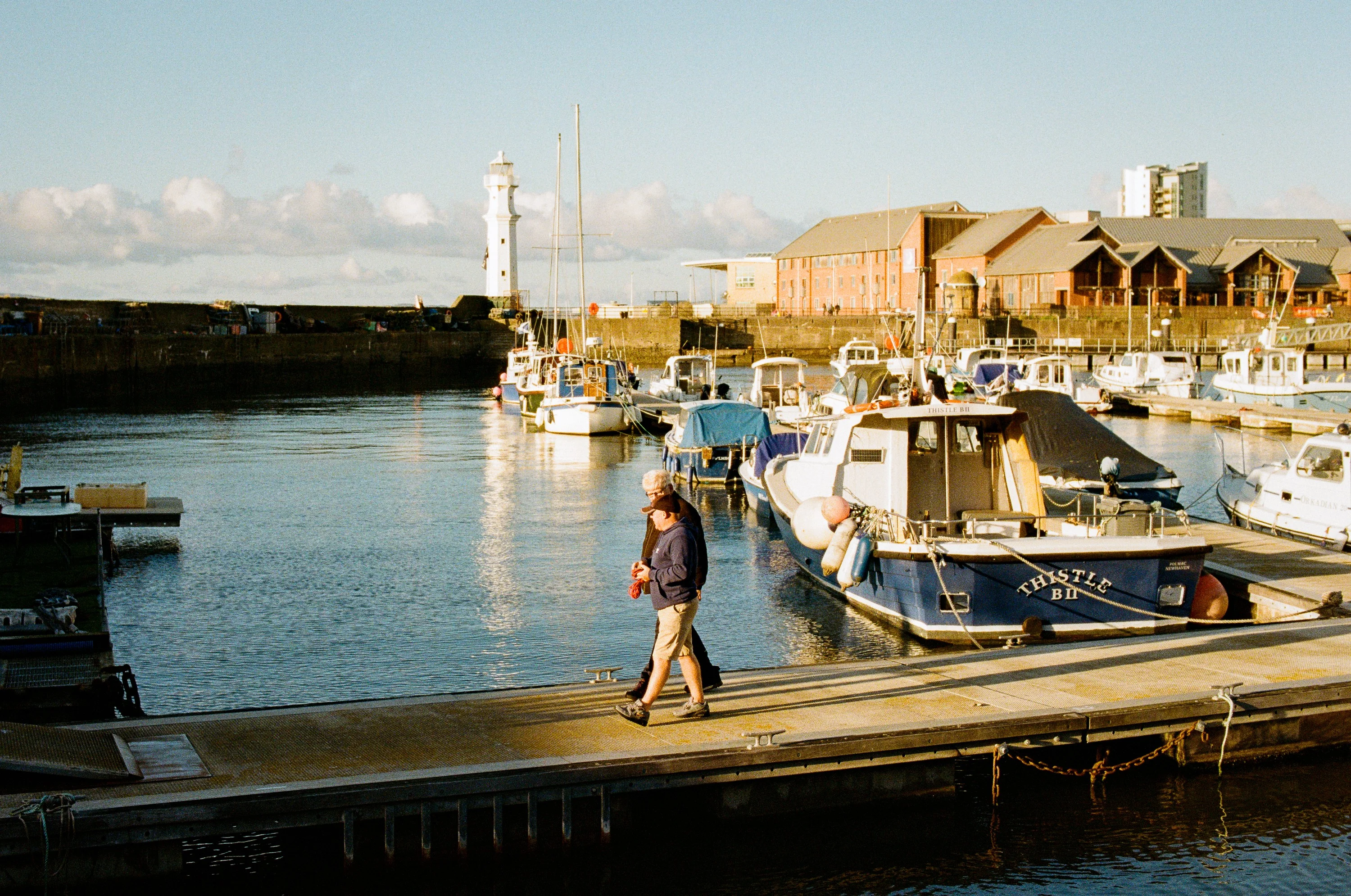 A man walking along a pontoon among moored boats at Newhaven