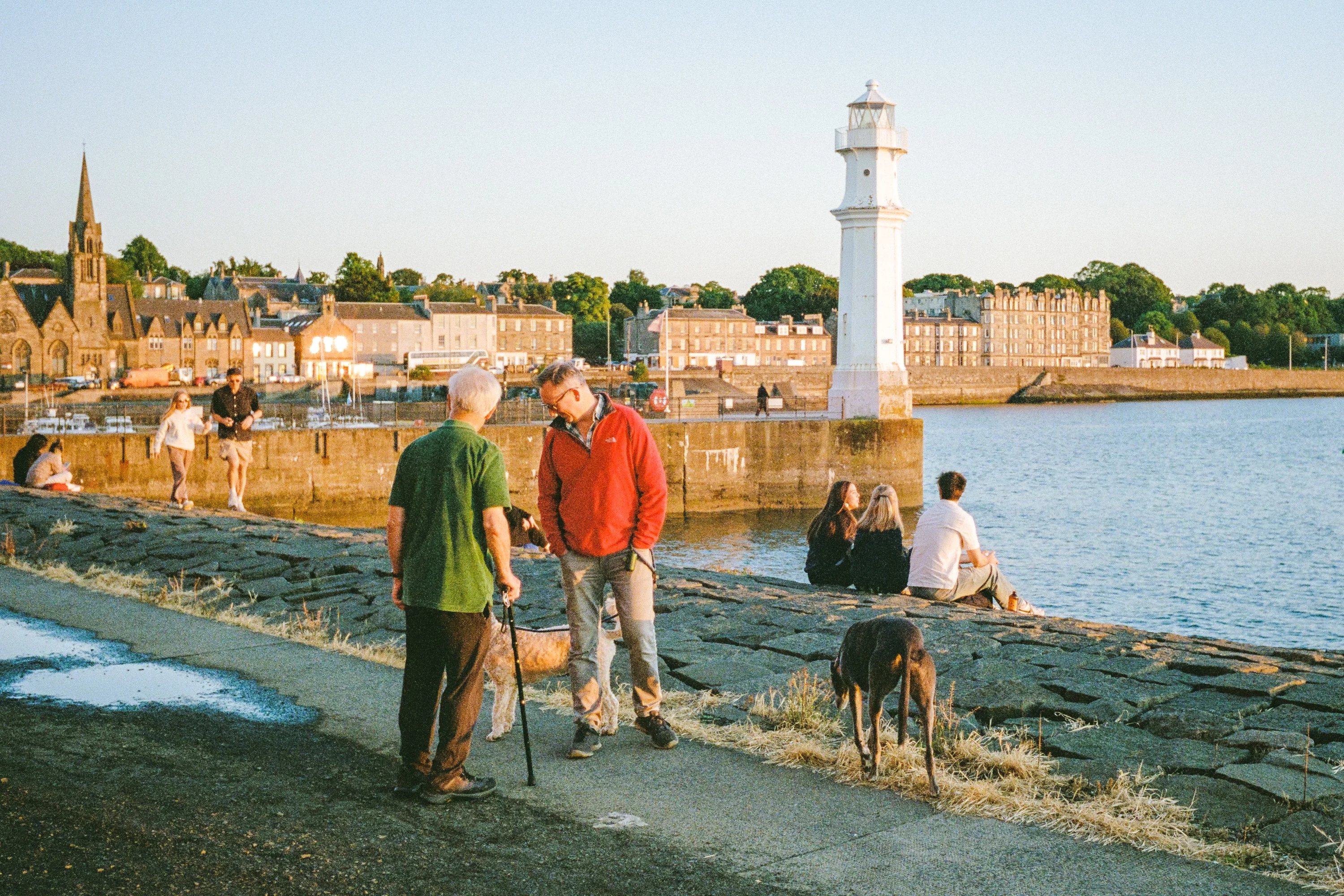 People and a dog on the harbour wall at Newhaven, the lighthouse behind