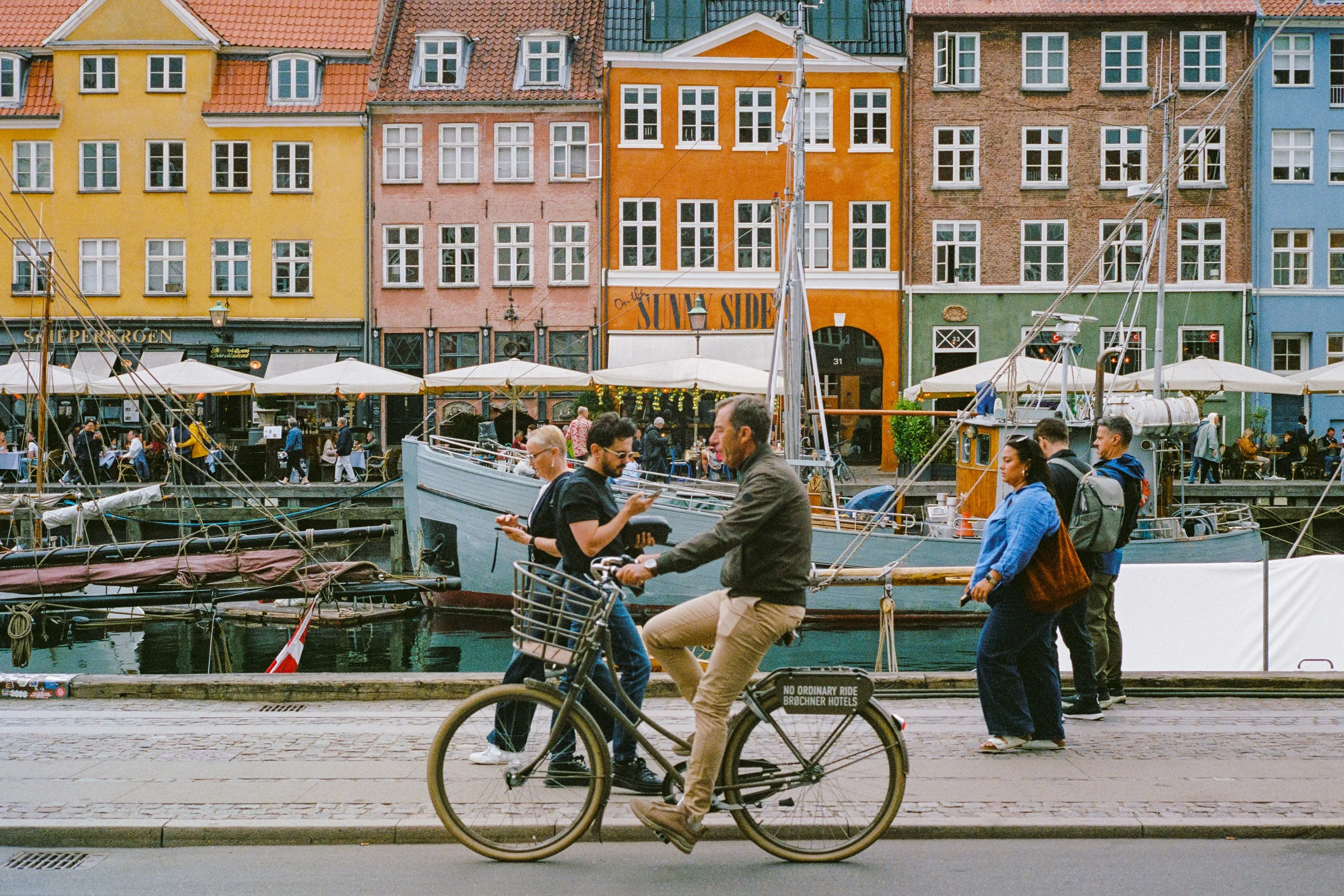 A cyclist passing the coloured houses and boats of Nyhavn