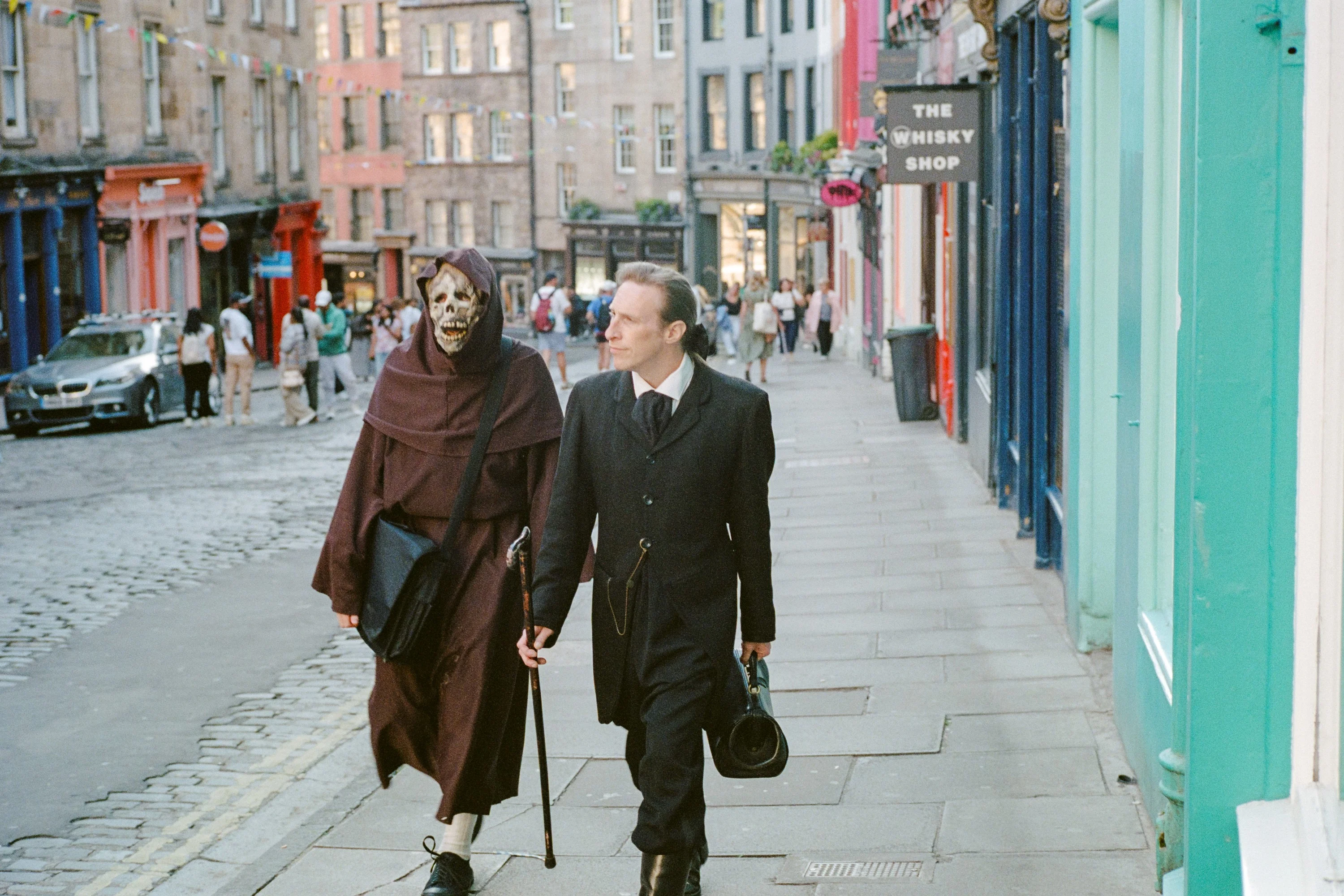 A man in a reaper costume walking with a man in a suit