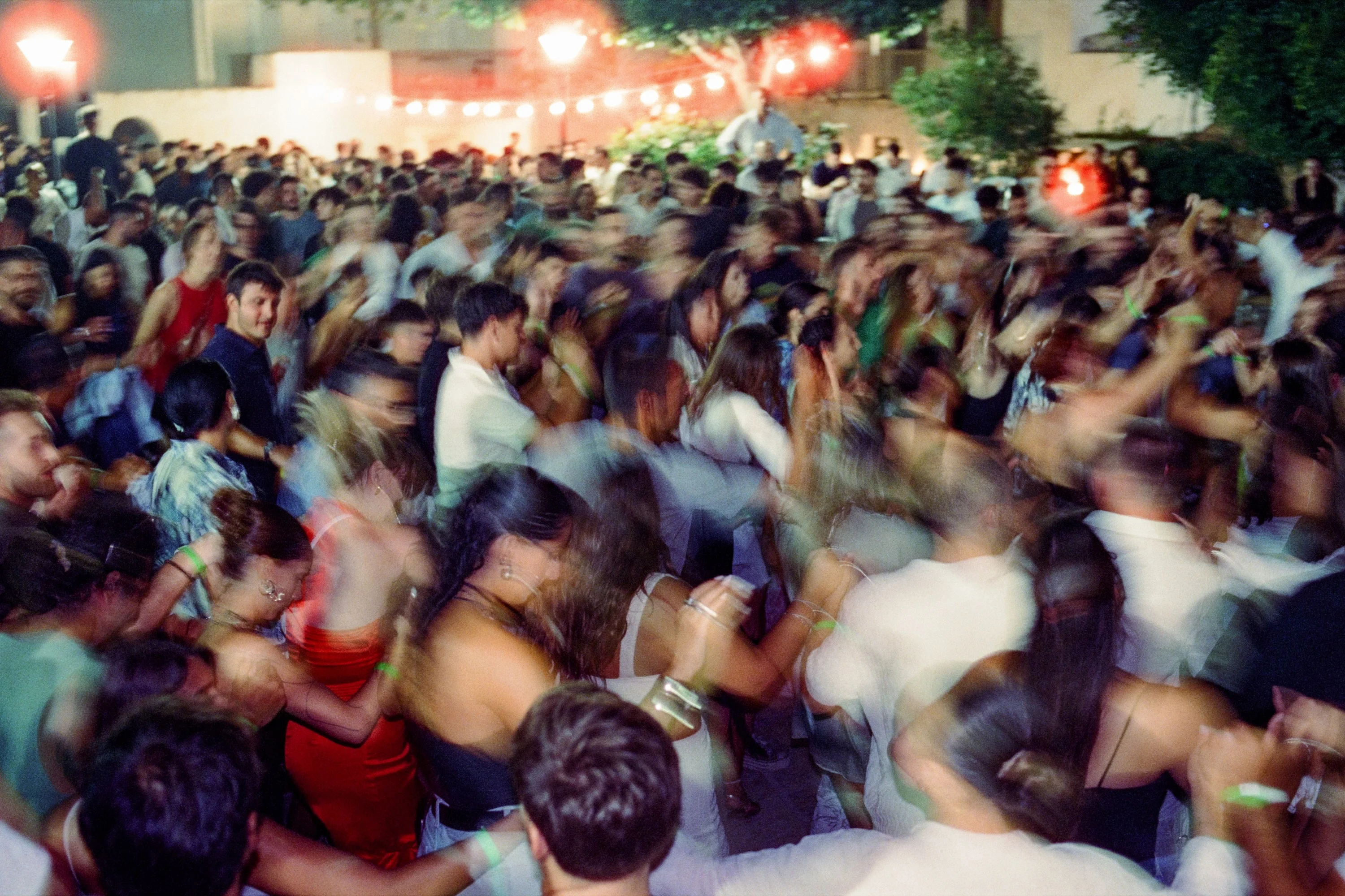 Dancers blurred in motion in a crowded square at night
