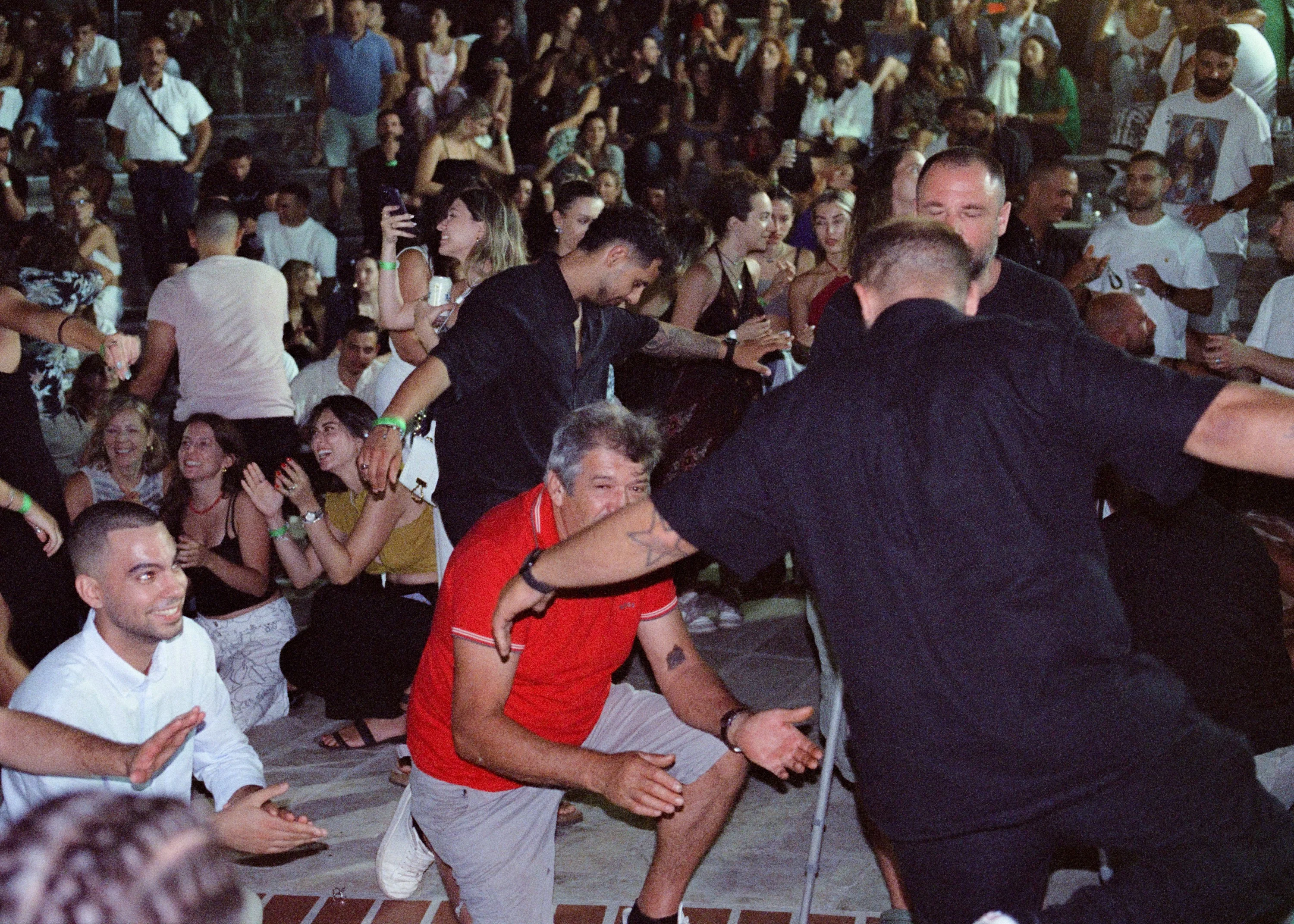 Men kneeling and clapping in a circle of dancers at a night festival