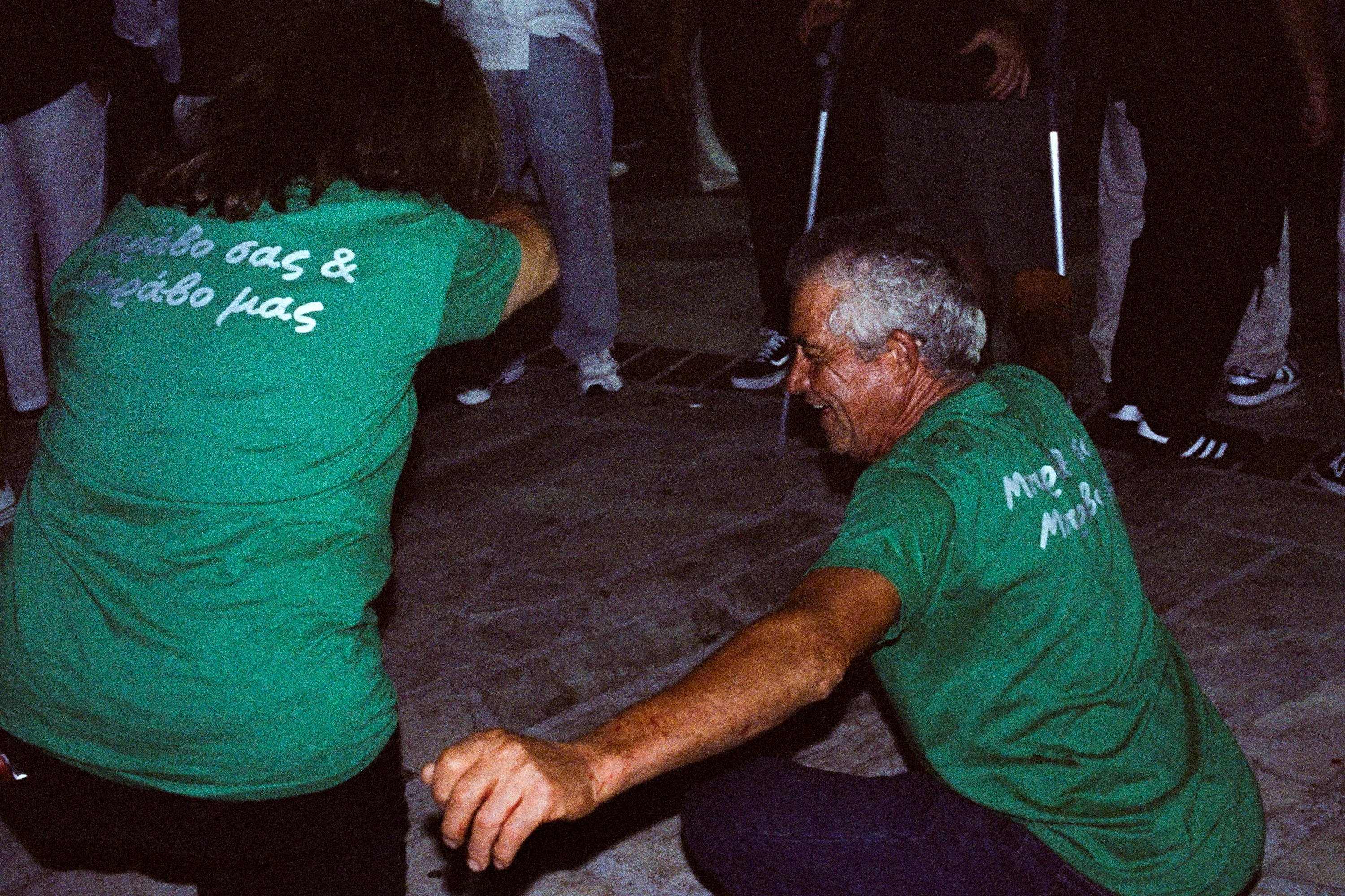 Two men in green festival shirts dancing low to the ground