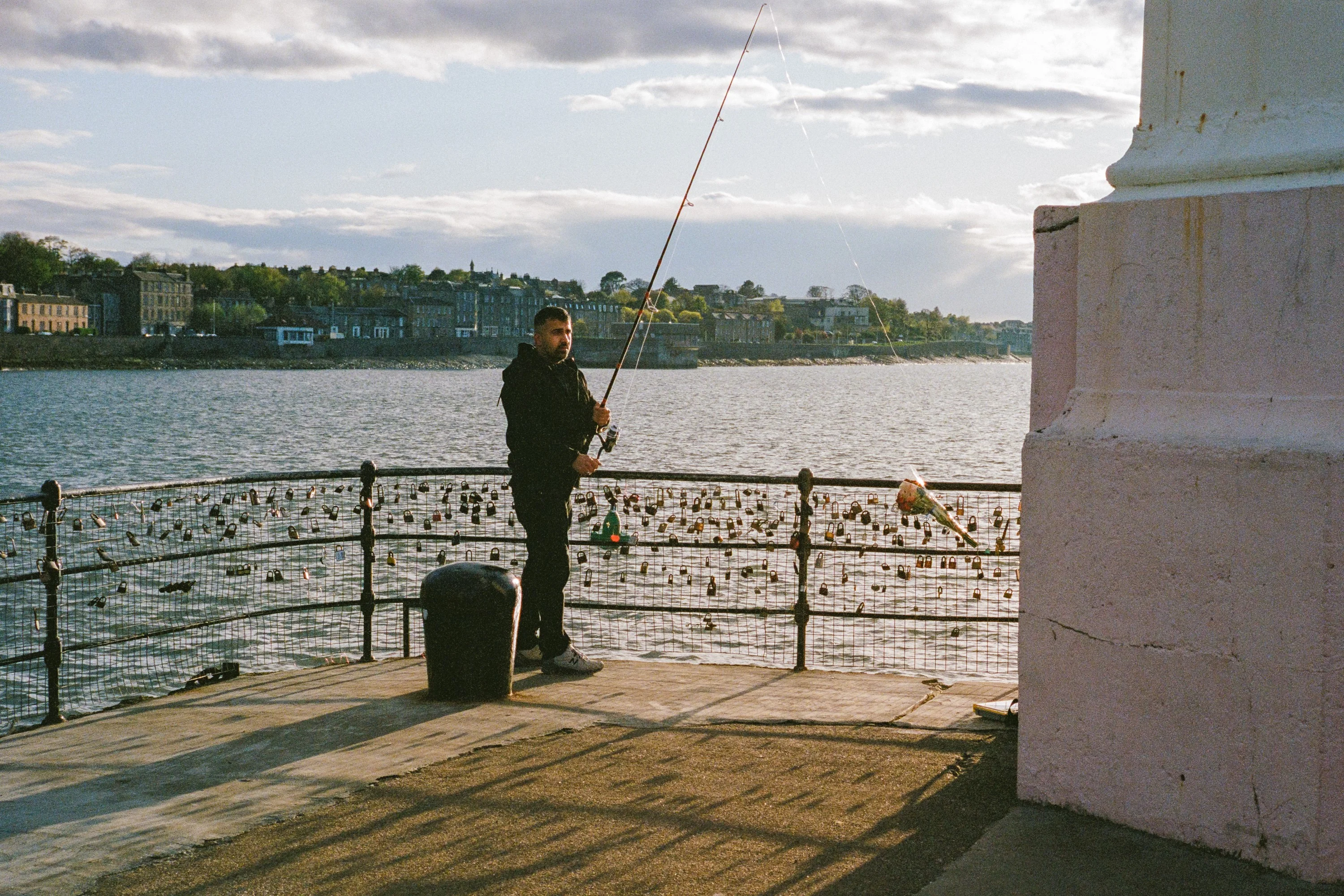 A man fishing from a pier beside a white column