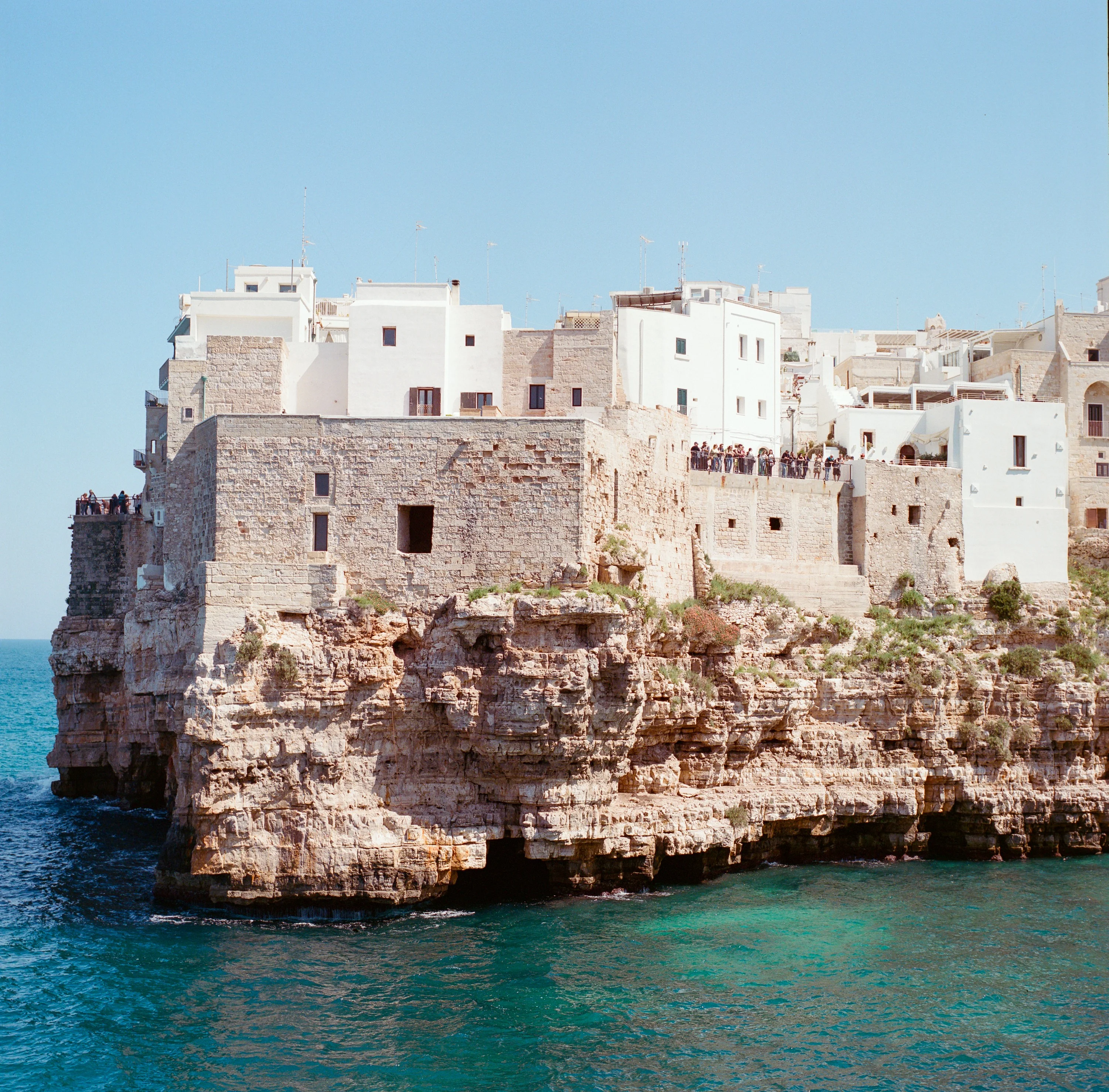 White houses on top of limestone cliffs above turquoise water