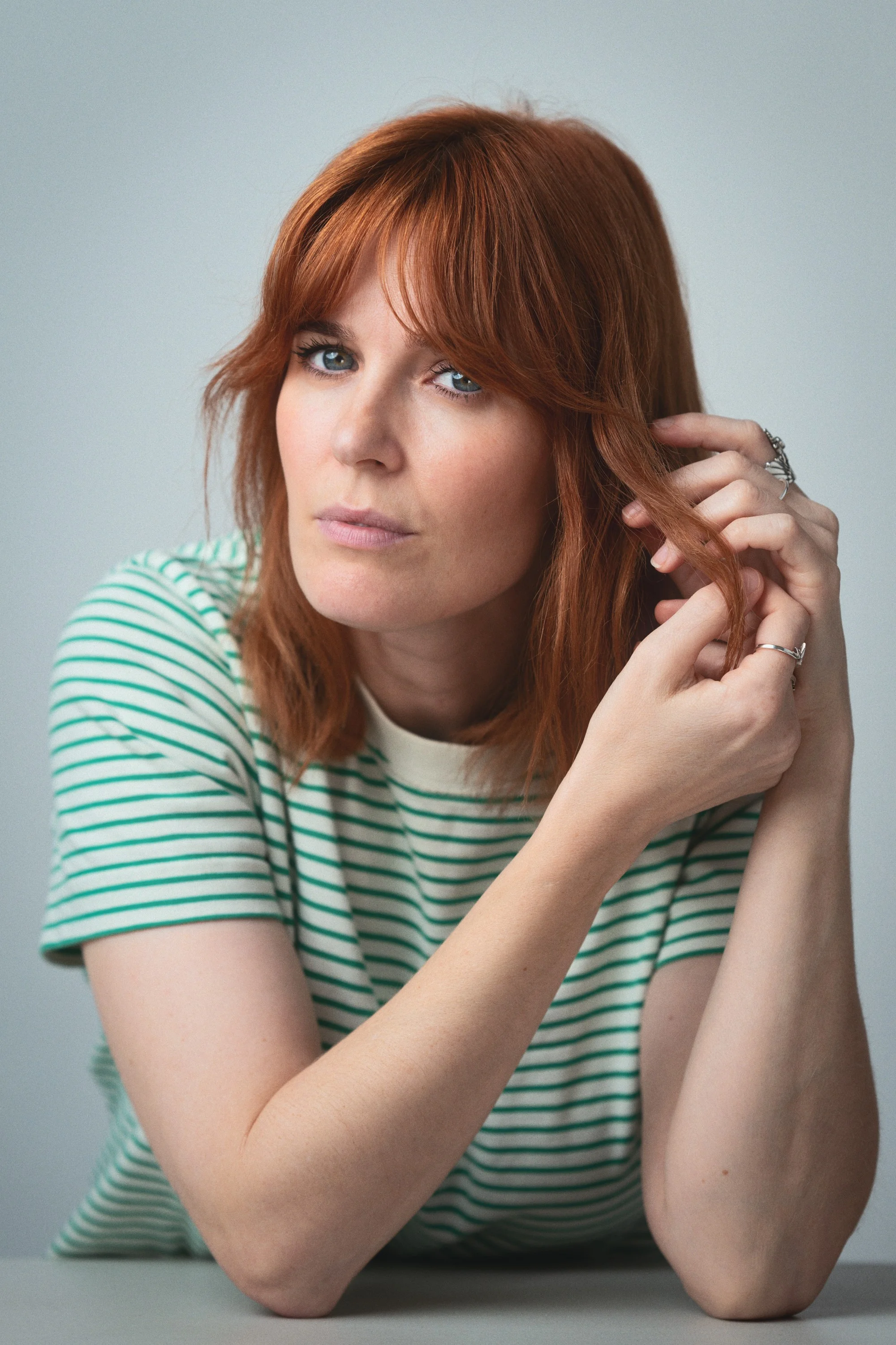 Portrait of a woman with red hair in a green and white striped t-shirt