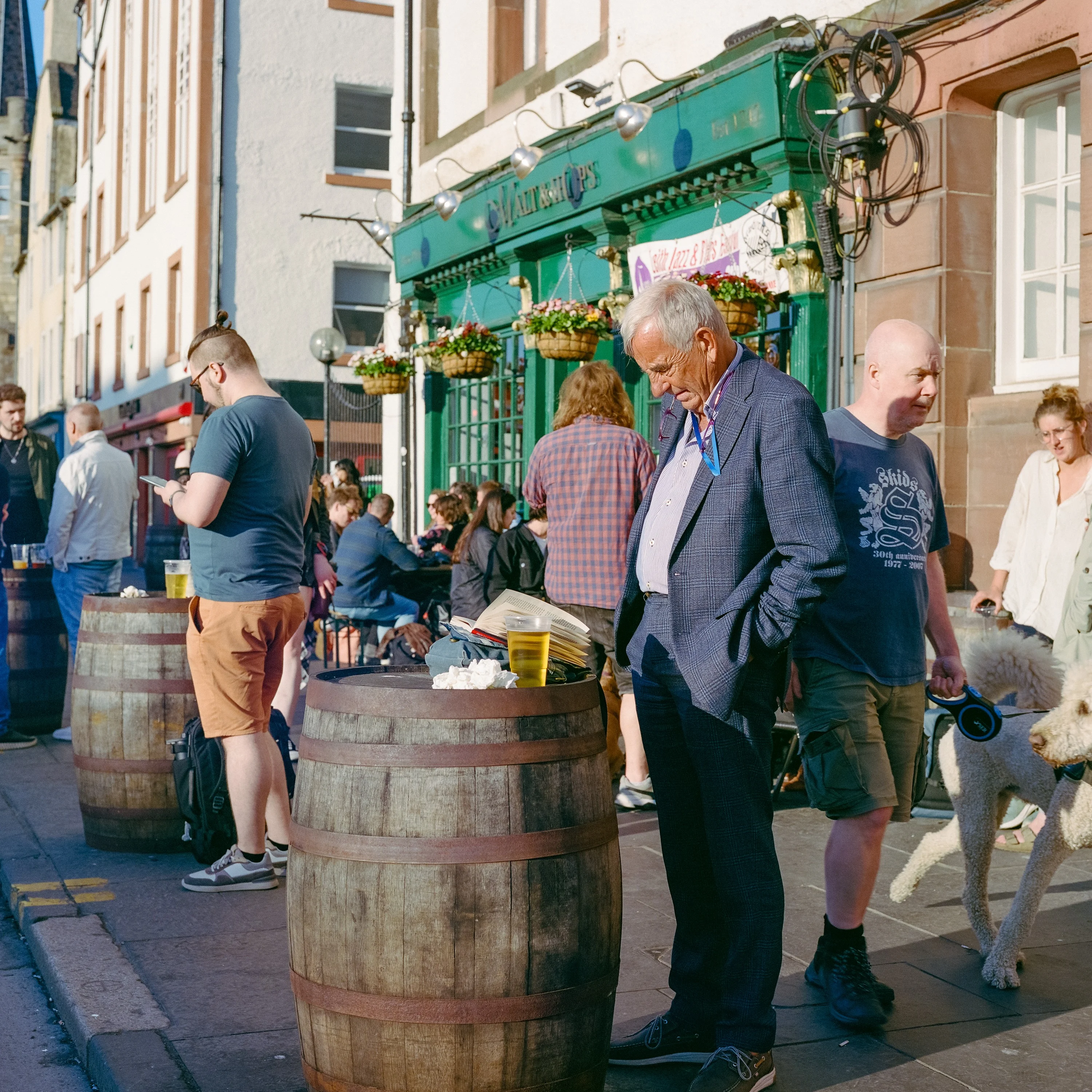 People drinking around barrels outside a green pub