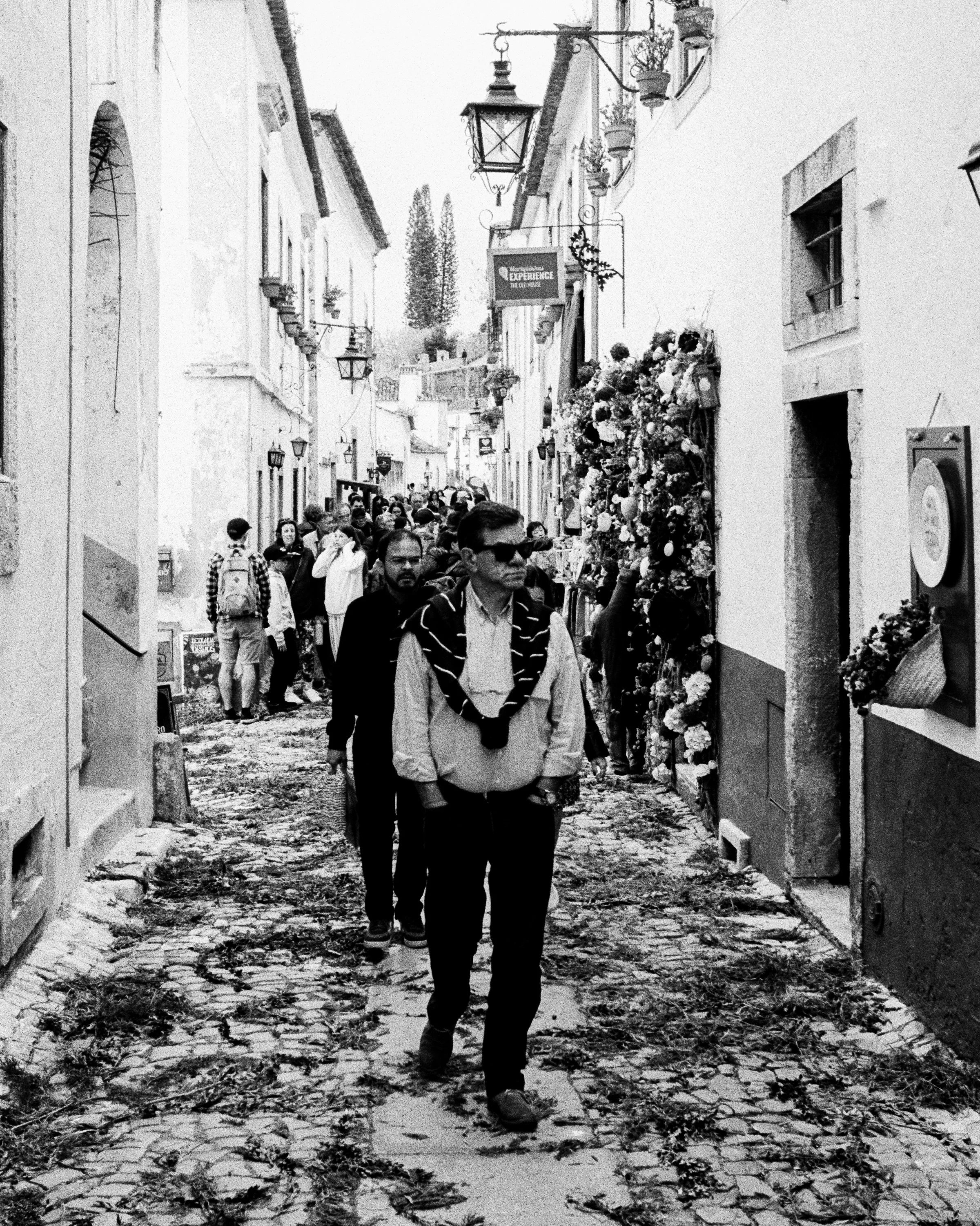 Black and white: a man walking down a street strewn with leaves