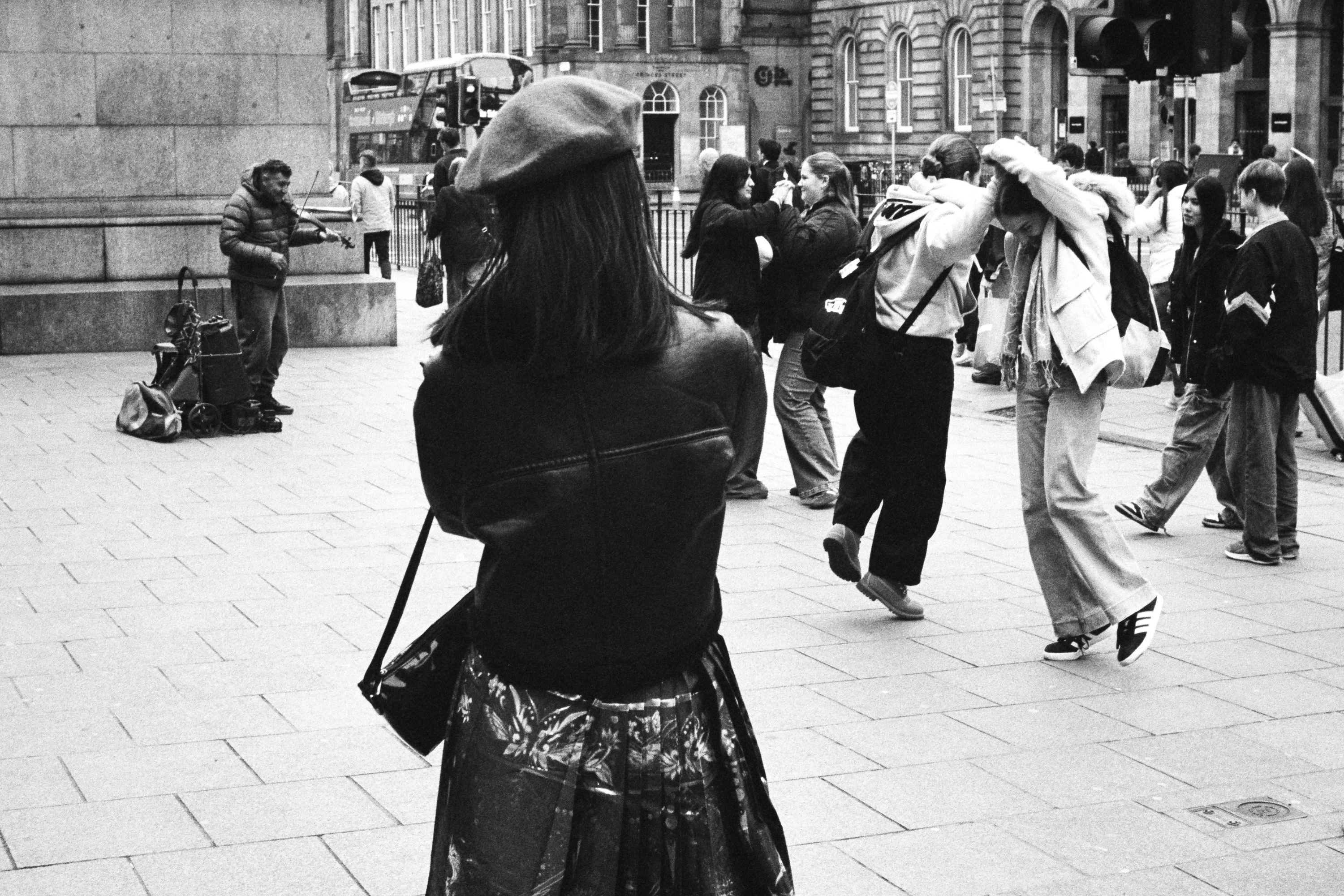 Black and white: people dancing in a square, a woman in a beret in front