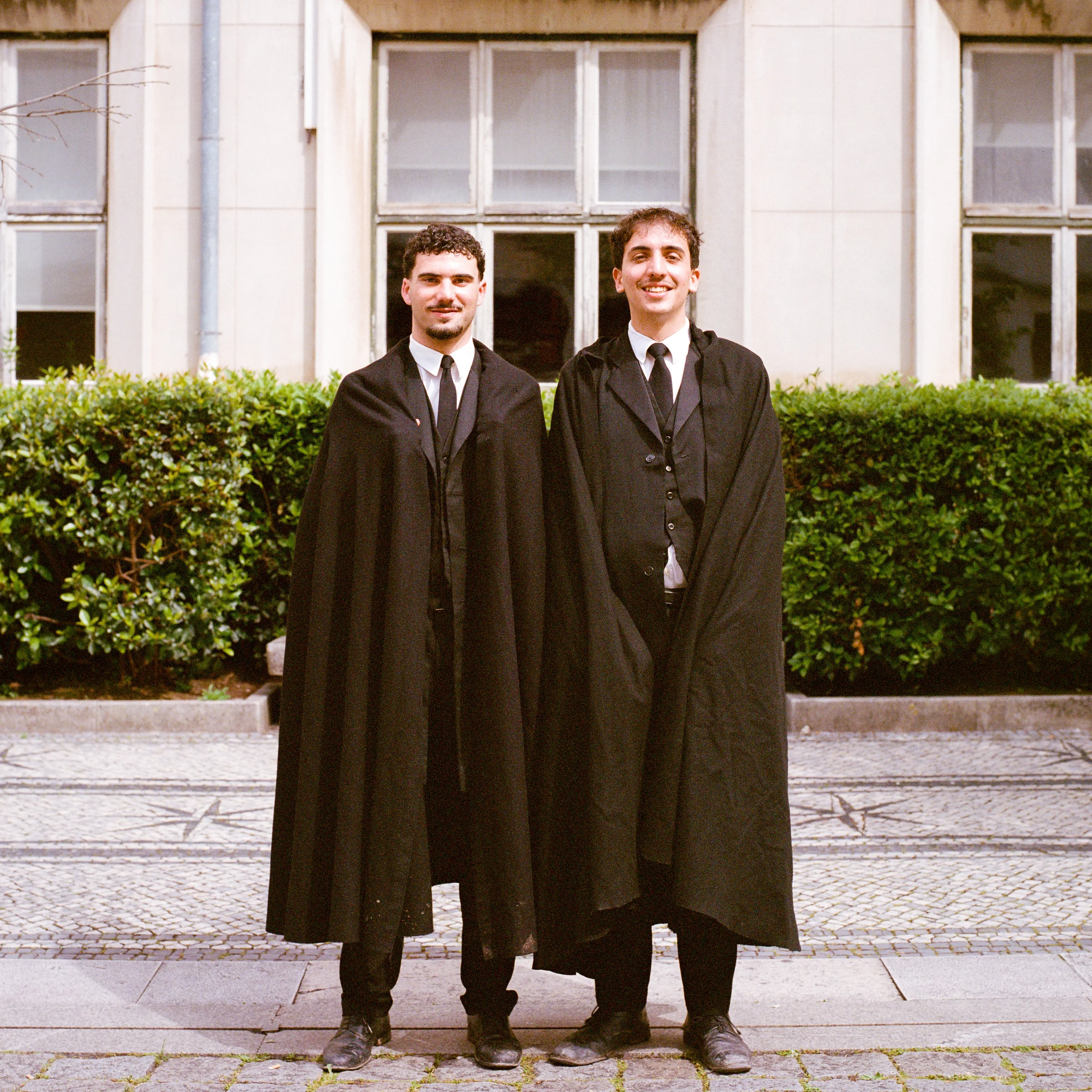 Two students in black capes standing side by side