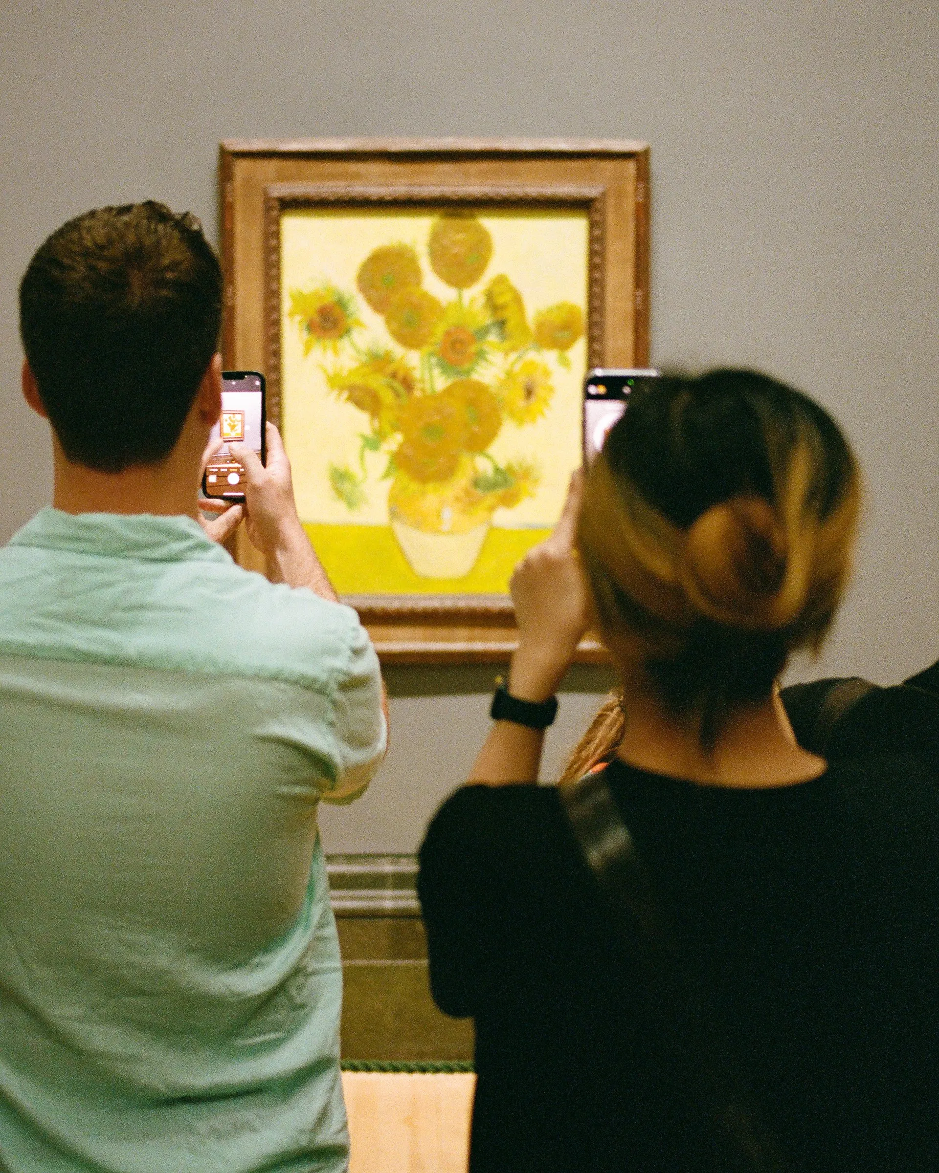 Two visitors photograph Van Gogh's Sunflowers on their phones