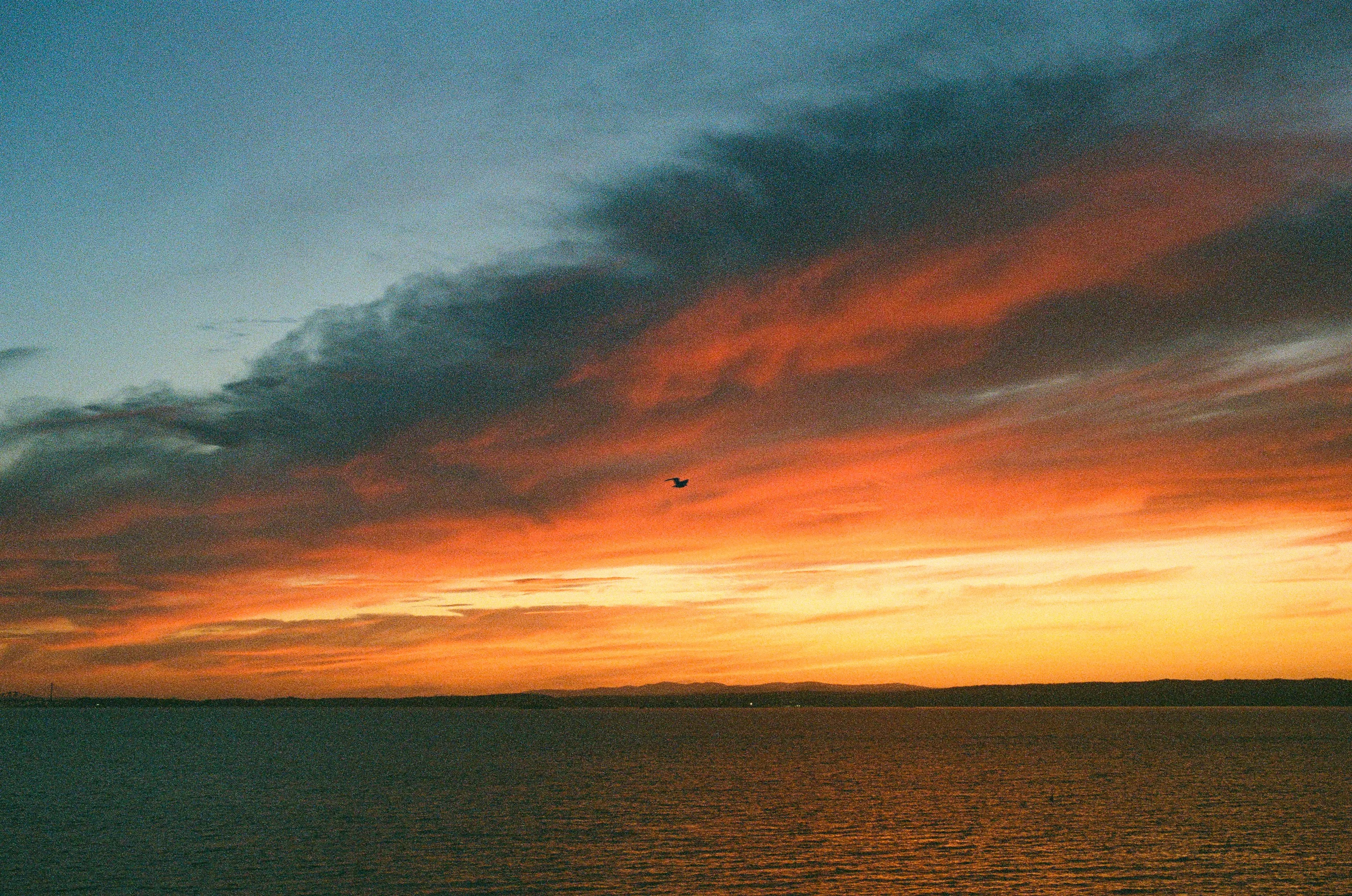 A band of orange cloud over dark water at sunset