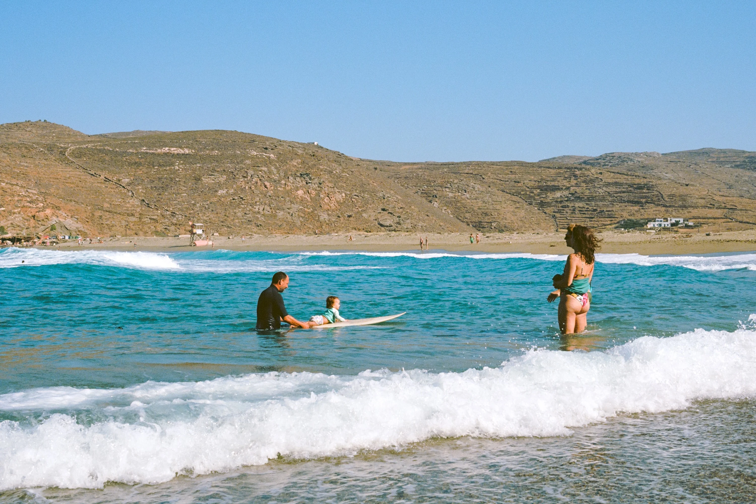 Swimmers wading into breaking waves below dry hills
