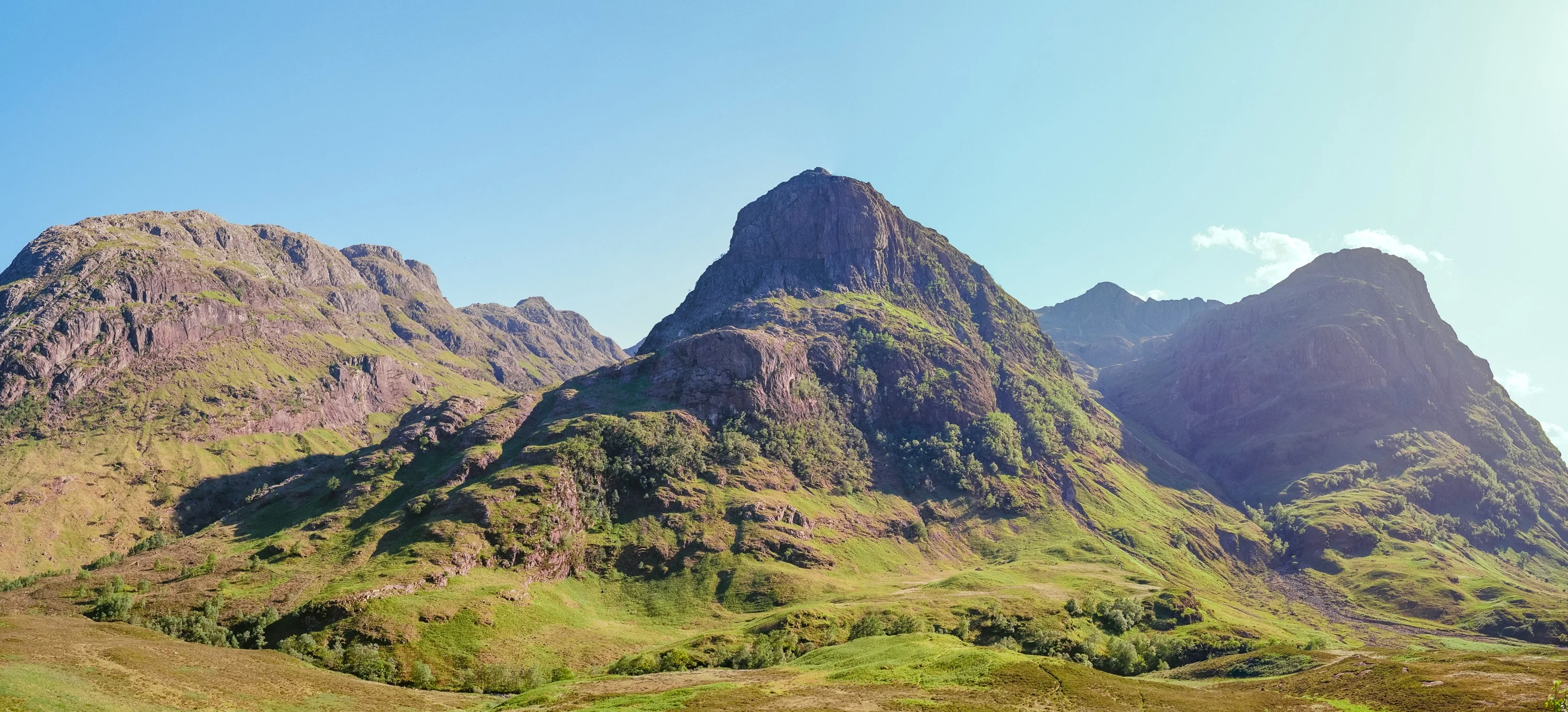 A panorama of the Three Sisters of Glencoe in green summer light