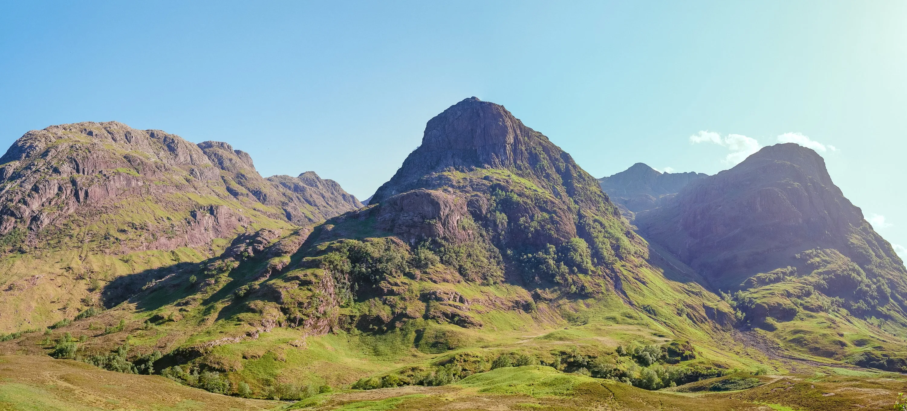 A panorama of the Three Sisters of Glencoe in green summer light