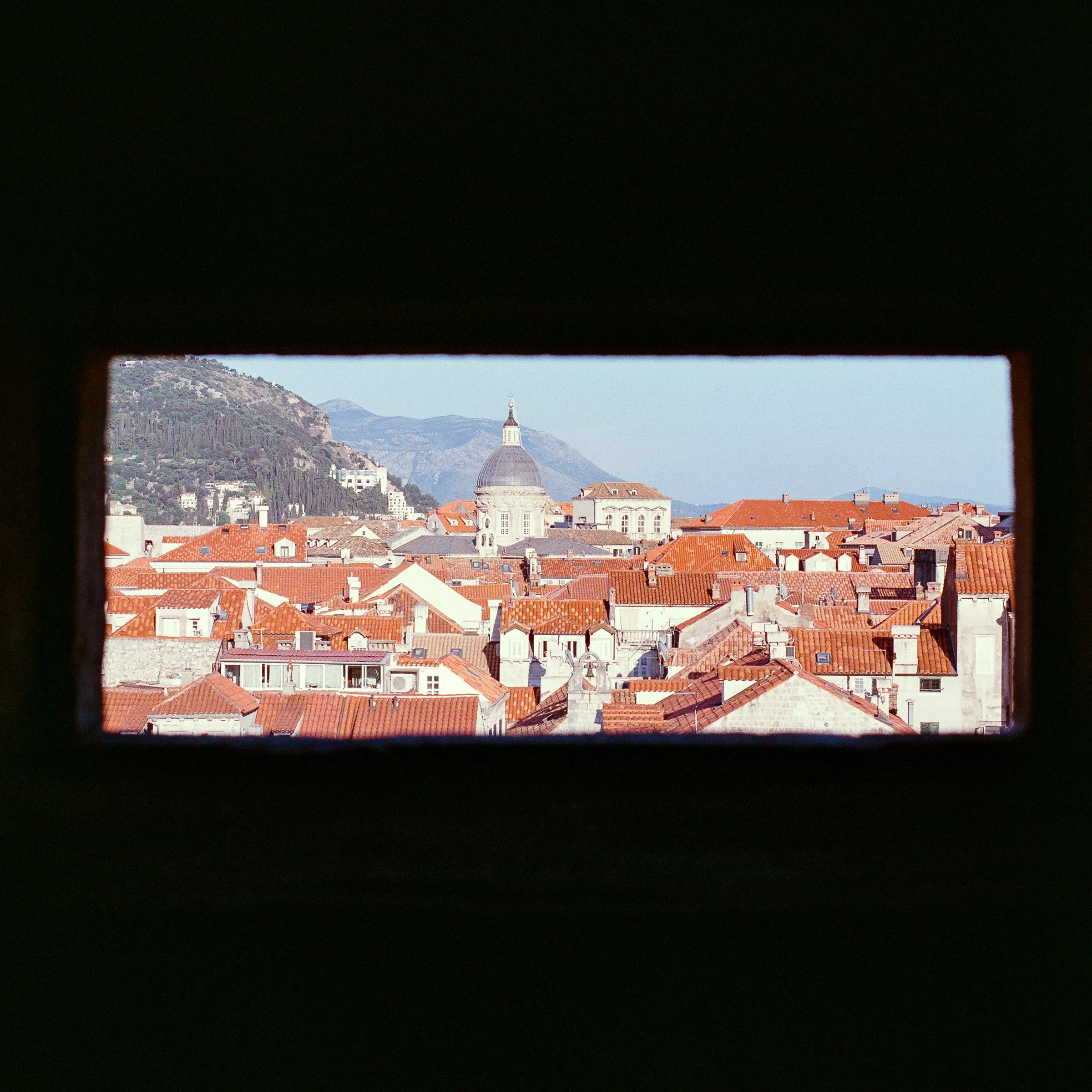 Terracotta rooftops seen through a narrow slot in the city wall