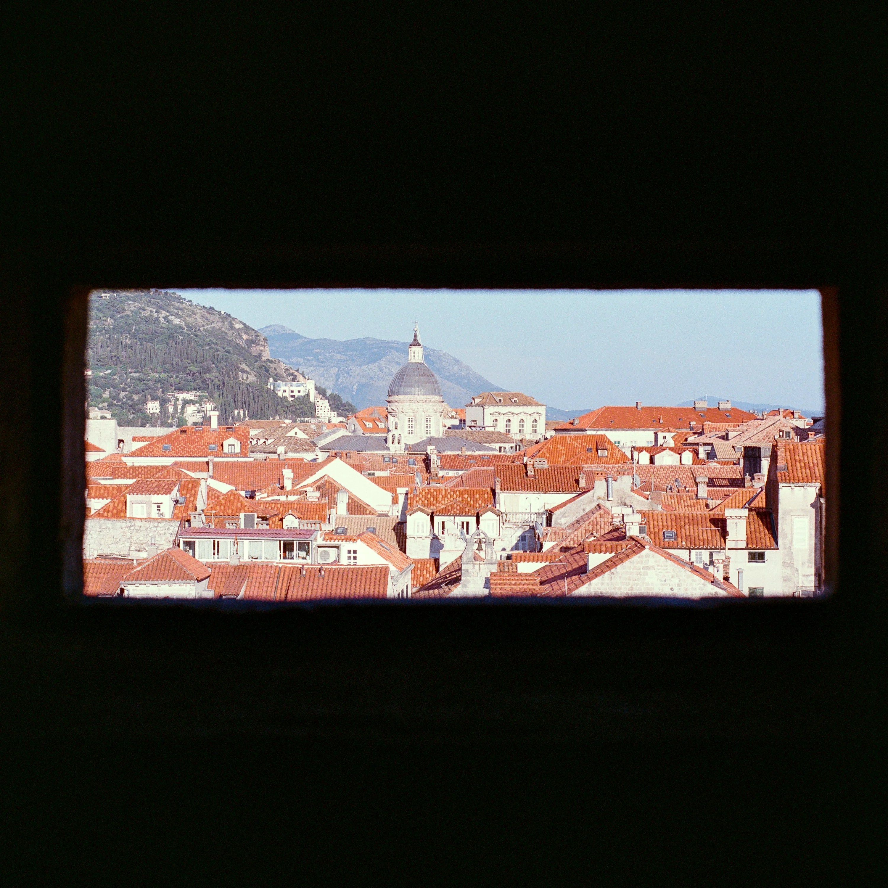 Terracotta rooftops seen through a narrow slot in the city wall